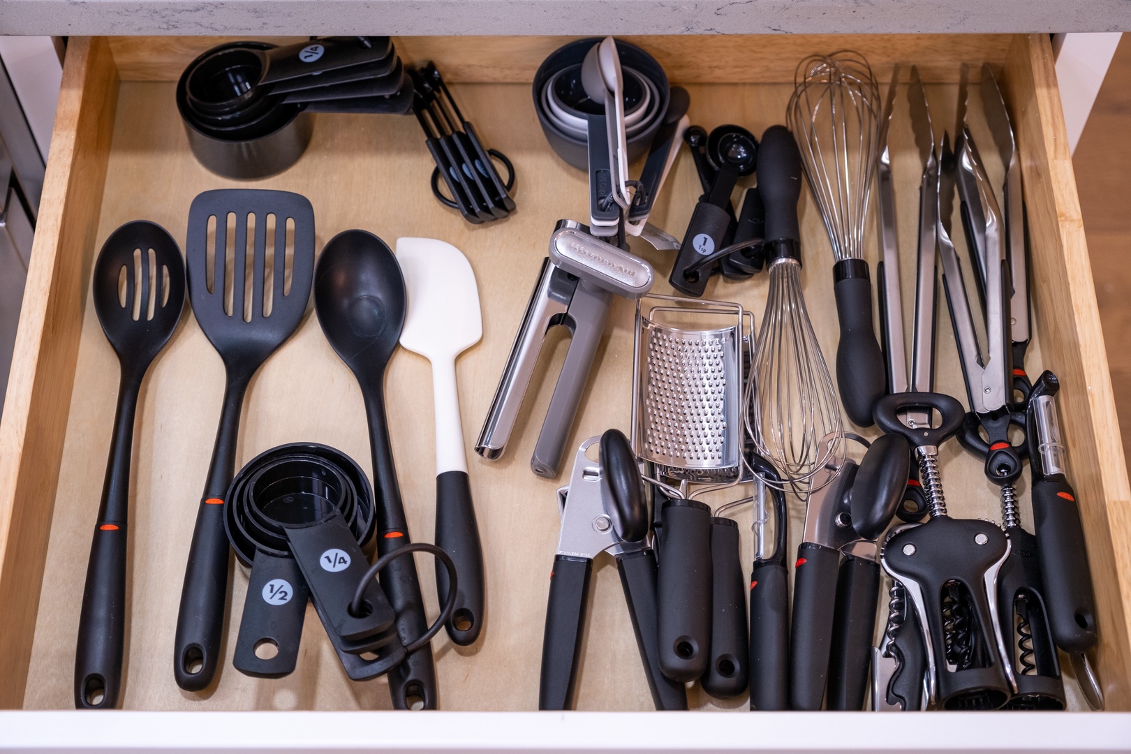 A fully stocked kitchen drawer with professional-grade utensils, from whisks and measuring spoons to graters and can openers—everything you need to cook like a chef during your stay.