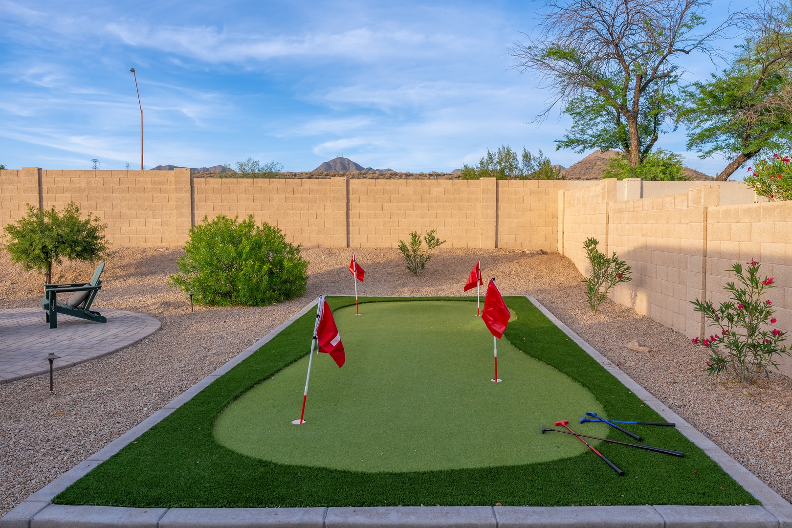 Practice your putting stroke on this private backyard mini golf green, surrounded by desert landscaping and mountain views under open skies.