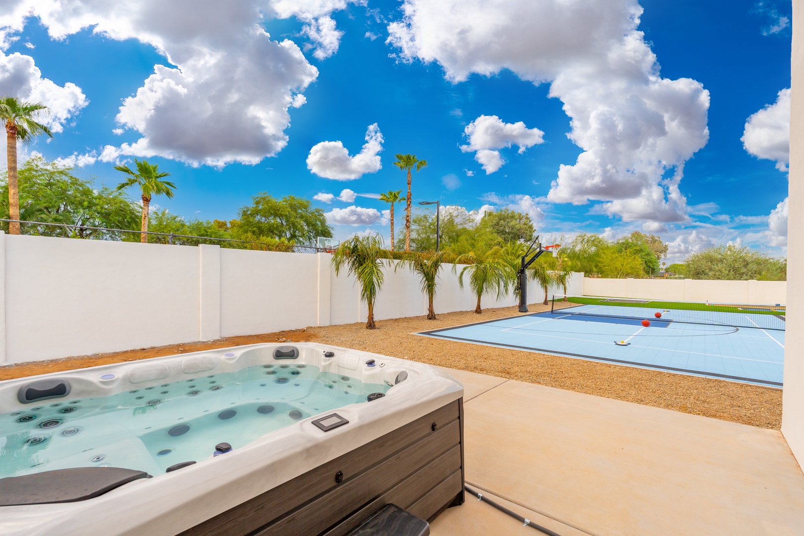 Soak in your private hot tub under the open sky, with a sparkling pool, lush palms, and endless sunshine creating your perfect backyard escape.