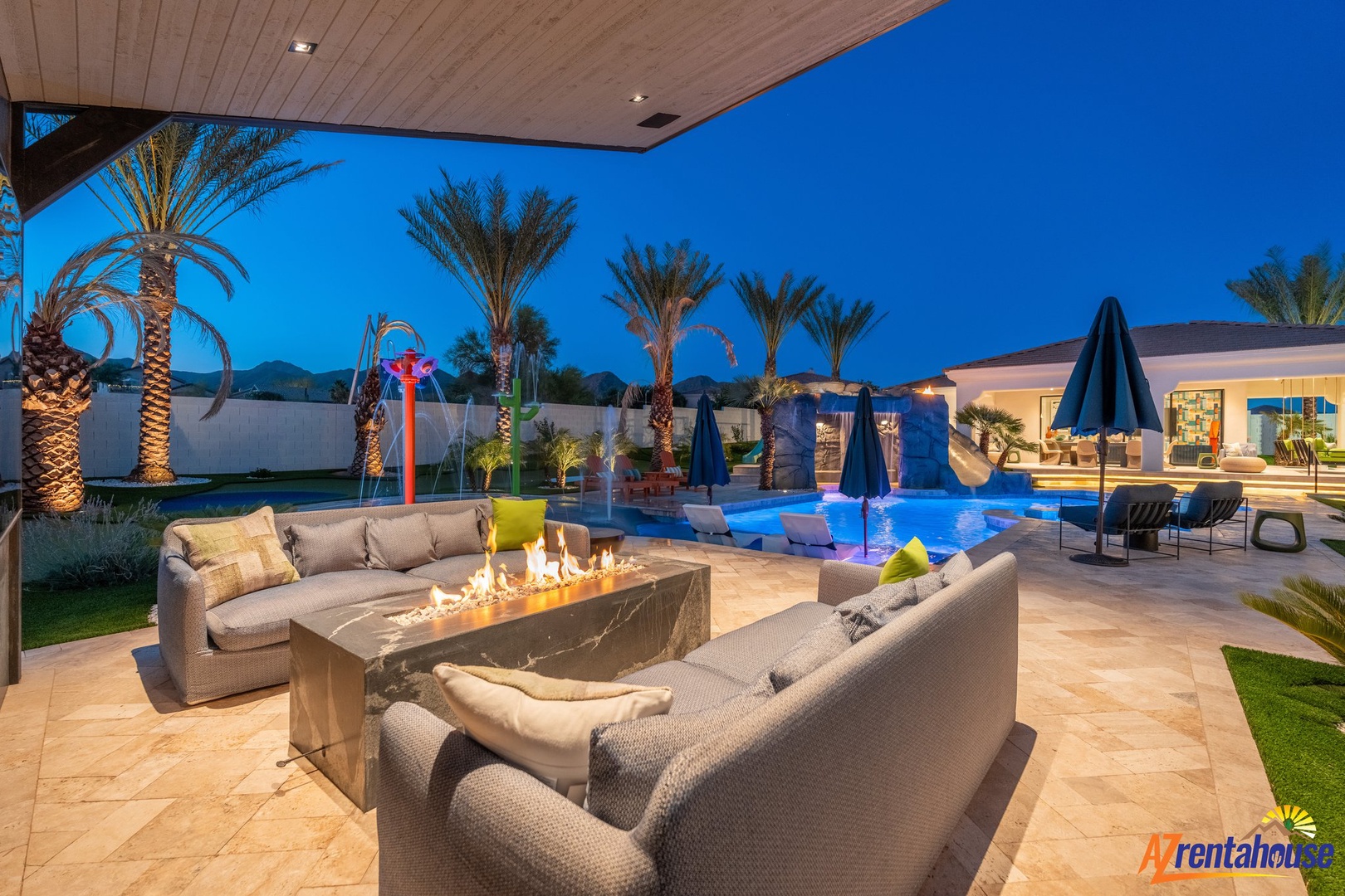 Unwind in your private oasis featuring a cozy fire pit lounge with elegant seating overlooking a sparkling pool area.