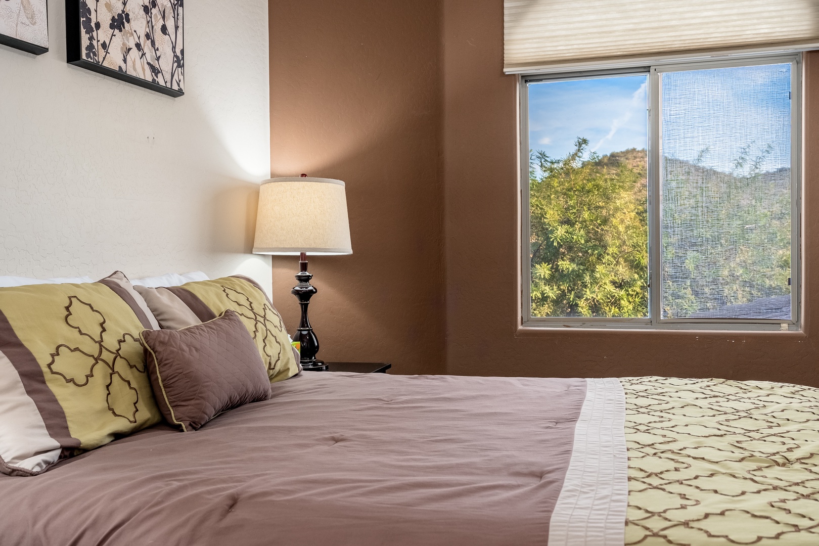 Wake up to natural light and mountain views through your large bedroom window, where earthy tones and plush bedding create a peaceful retreat for your stay.