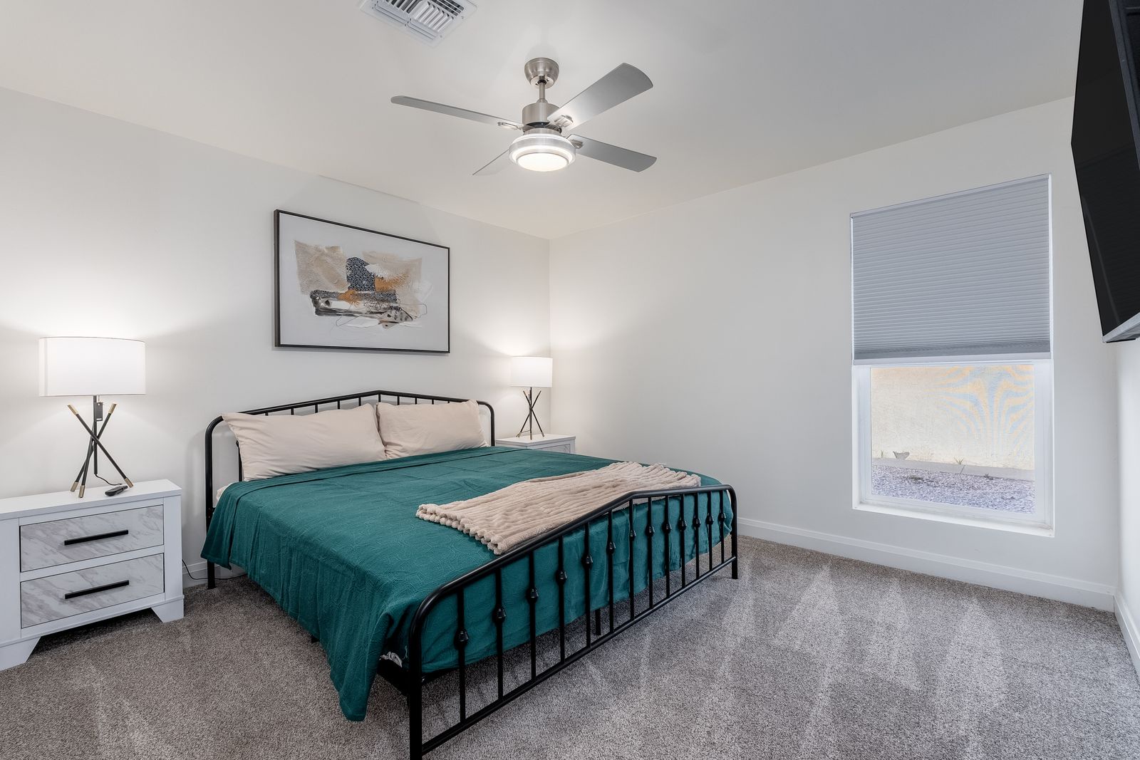 Unwind in this serene bedroom where soft linens and gentle ceiling fan breezes promise restful nights. Your peaceful retreat awaits with calming decor and natural light.