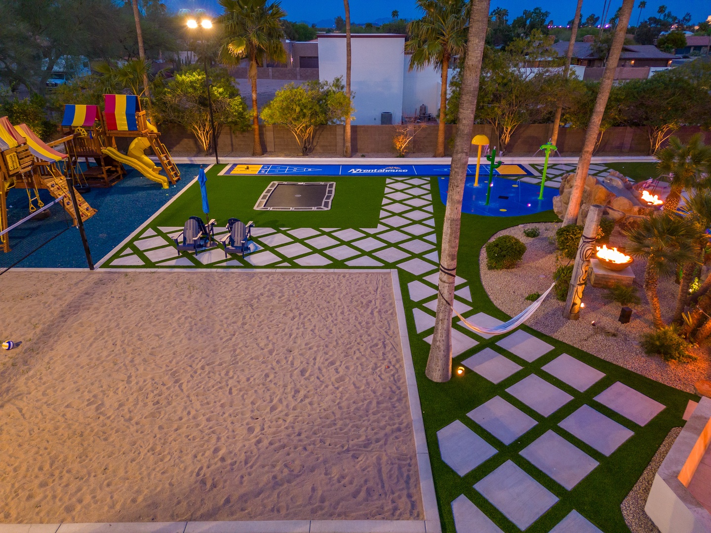 A resort-style backyard featuring a private beach volleyball court, playground with colorful slides, putting green, and fire features—your own entertainment paradise under swaying palms.