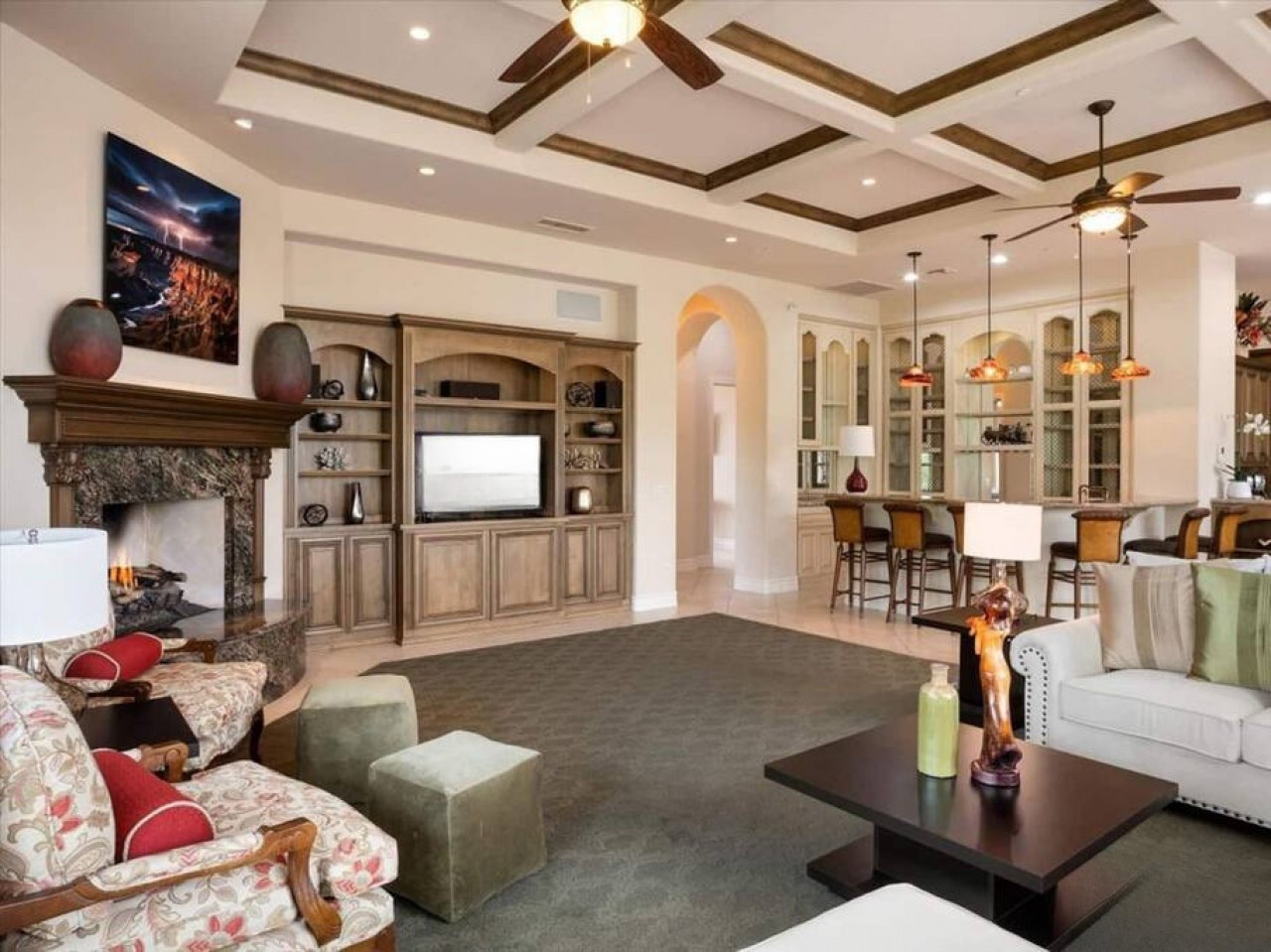 Gather in your open living space where warm wood tones and elegant ceiling beams frame your vacation moments by the cozy fireplace, with comfortable seating perfect for storytelling and laughter.