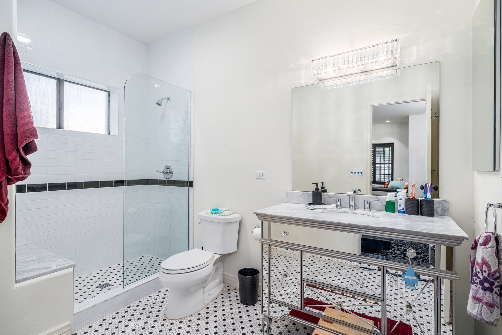 Step into your bright, modern bathroom with its stylish mirrored vanity, sparkling glass-enclosed shower, and elegant tile accents throughout.