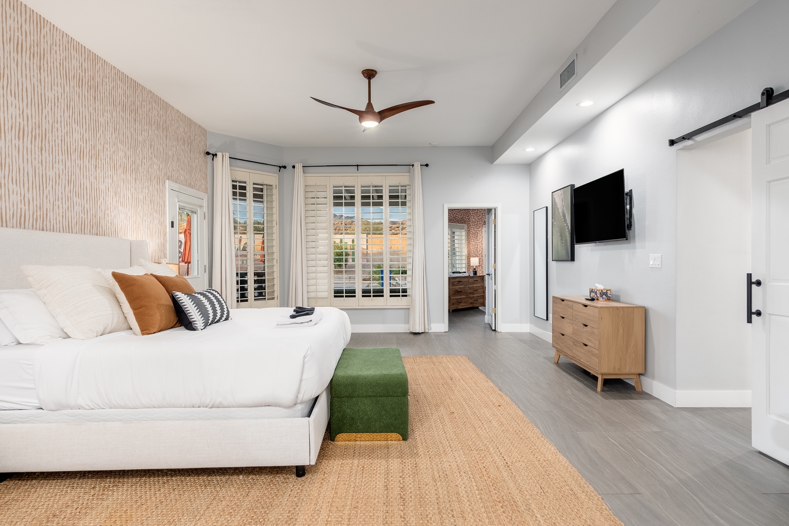 Sink into your plush king bed after a long day, with natural light streaming through plantation shutters and a smart TV ready for your evening entertainment.