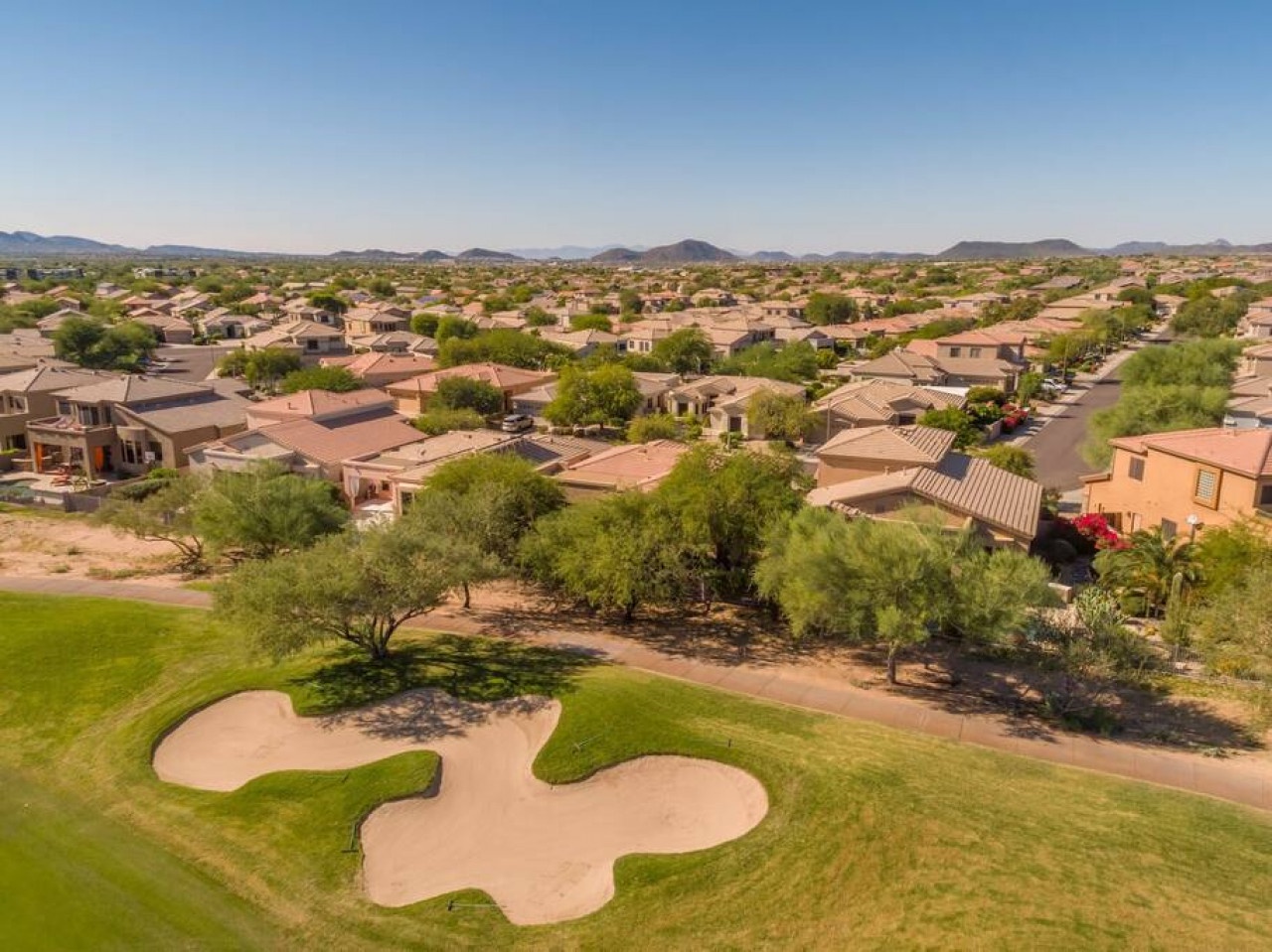 Aerial view showcases the desert community setting with well-maintained golf course and mountain backdrop surrounding the neighborhood.