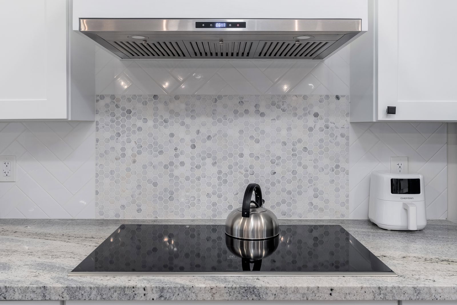You'll love the modern kitchen features, including a sleek induction cooktop, stylish hexagonal backsplash, and powerful range hood to keep the air fresh while you prepare delicious meals.