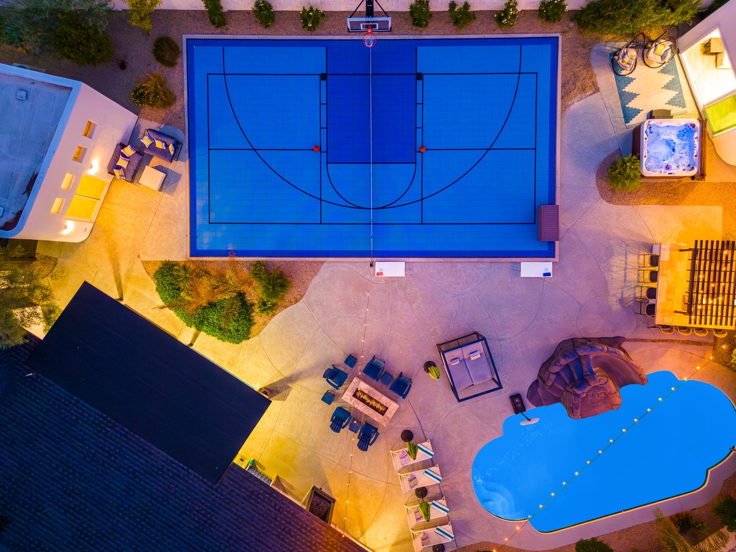 Aerial view showcasing the property's impressive outdoor recreational facilities, including a full-size basketball court, resort-style pool, hot tub, and multiple entertainment areas surrounded by landscaped grounds.