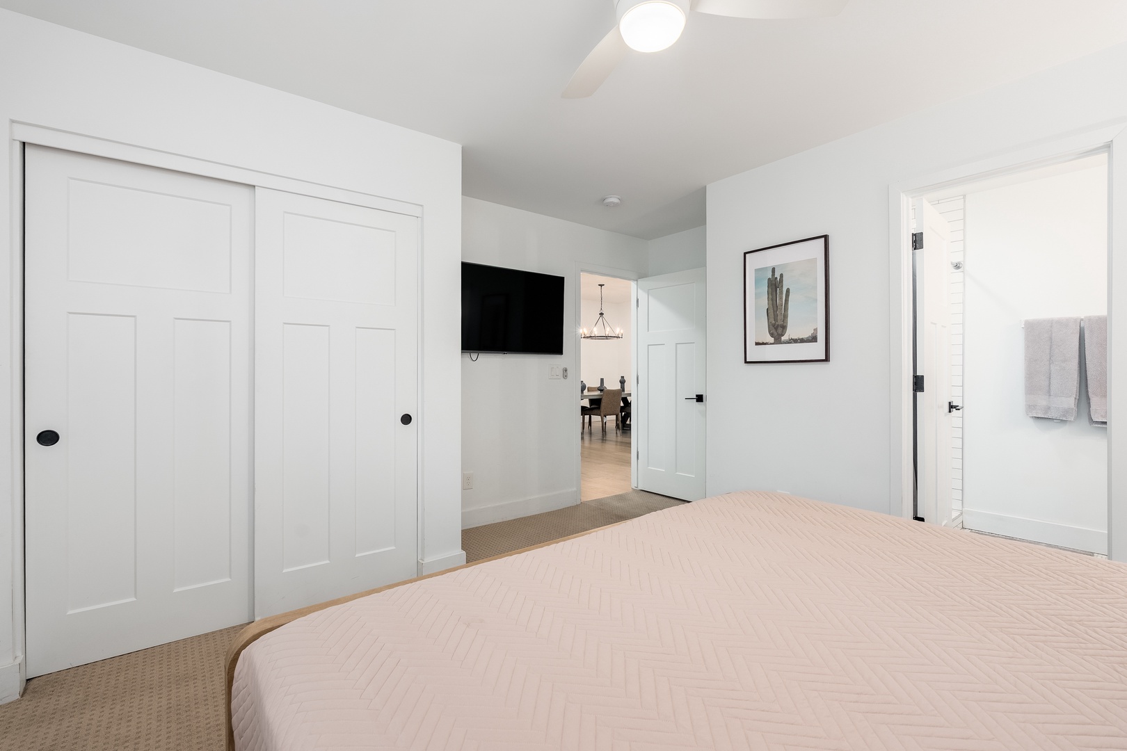Your serene bedroom offers plush bedding, a wall-mounted TV for relaxation, and an ensuite bathroom with fresh towels—everything you need for a restful stay.