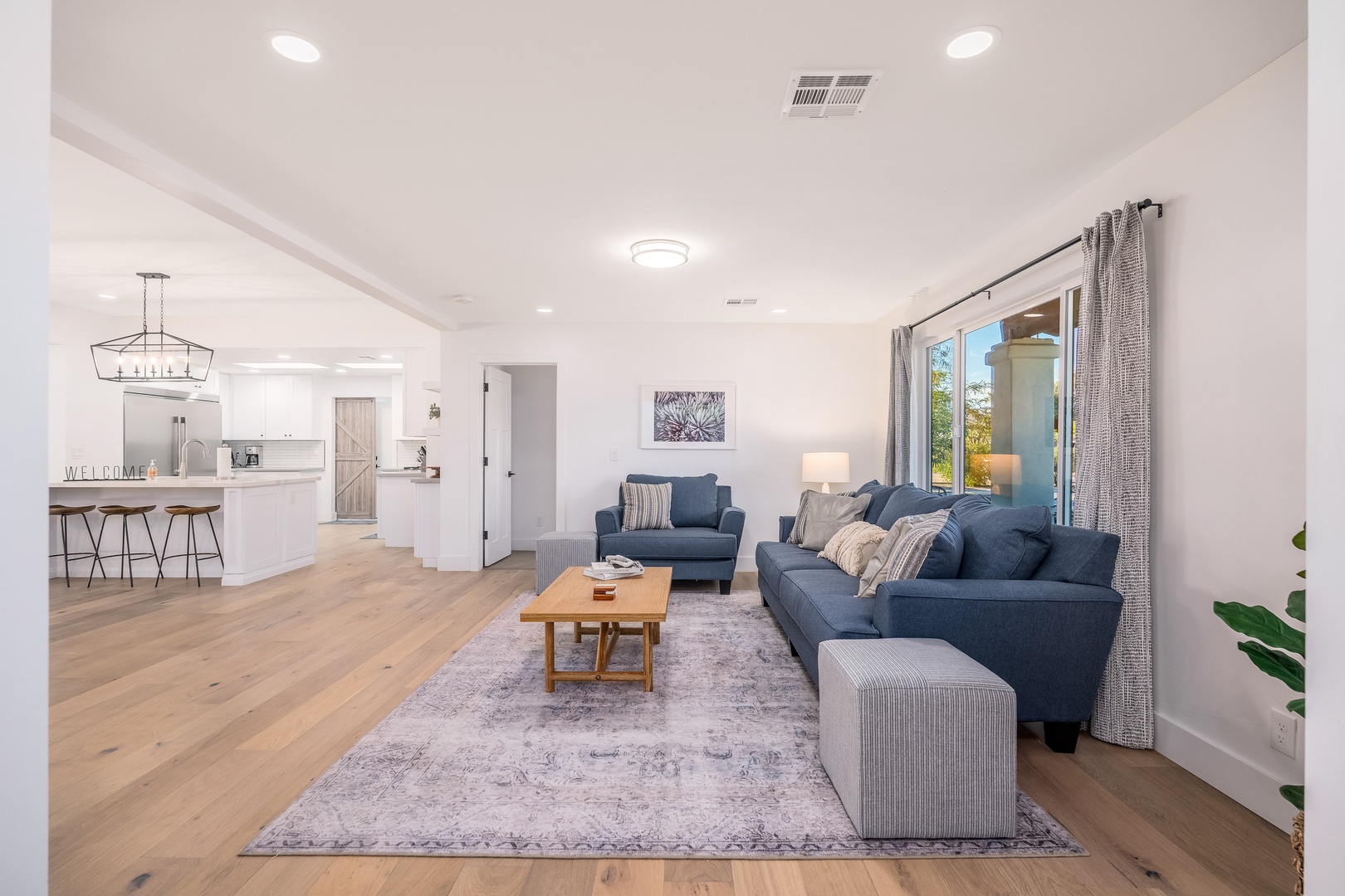 Settle into this sun-drenched living space where vaulted ceilings and open-plan design create an airy retreat. Sink into plush seating as natural light spills through the sliding glass door, inviting relaxation after a day exploring.