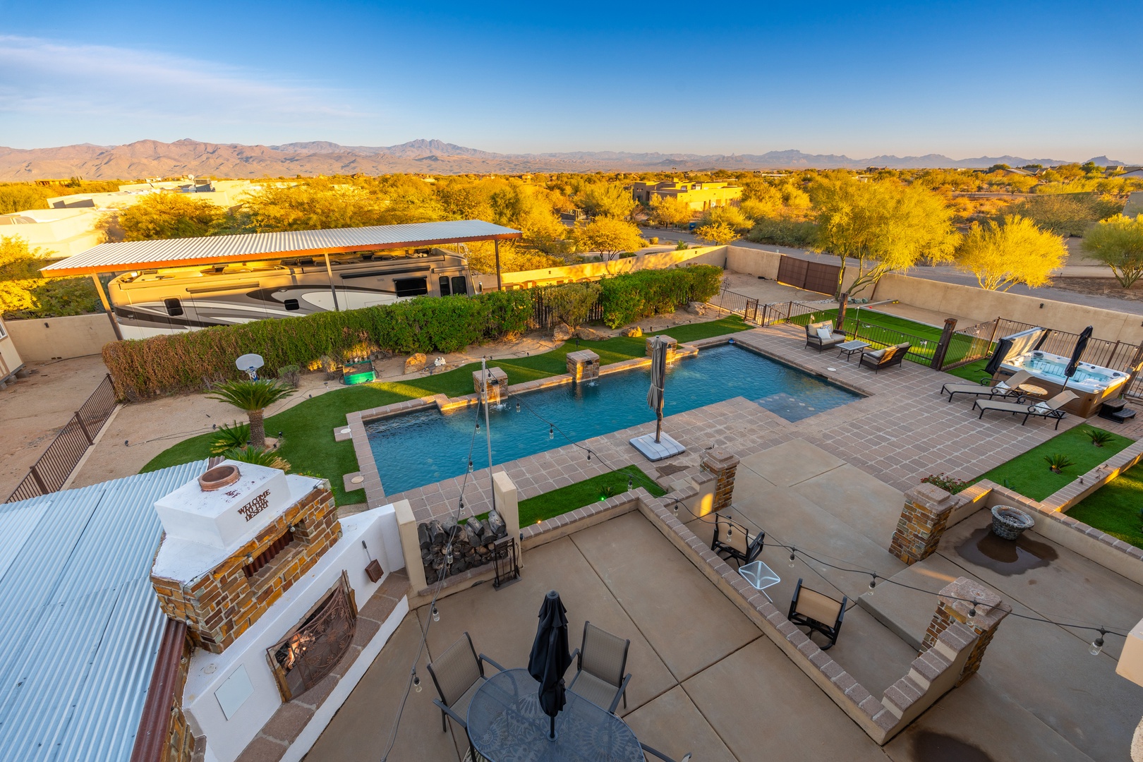 A sprawling desert retreat with pool, outdoor kitchen, and fire pit set against golden autumn foliage and distant mountain ranges—ideal for gatherings in warm, open-air comfort.