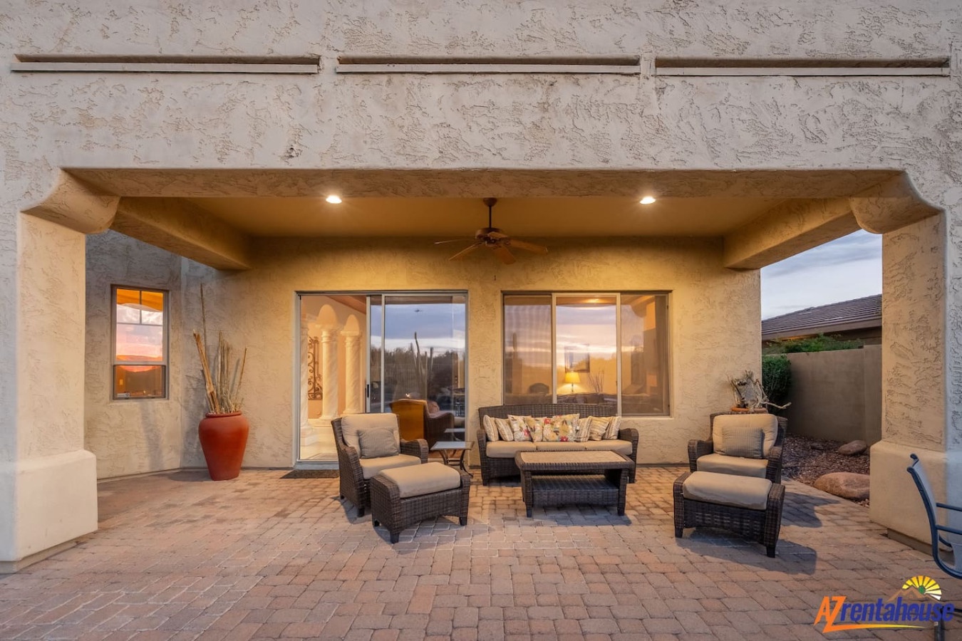 Relax in your spacious covered patio with comfortable seating and warm desert-inspired decor as golden hour light creates the perfect ambiance.