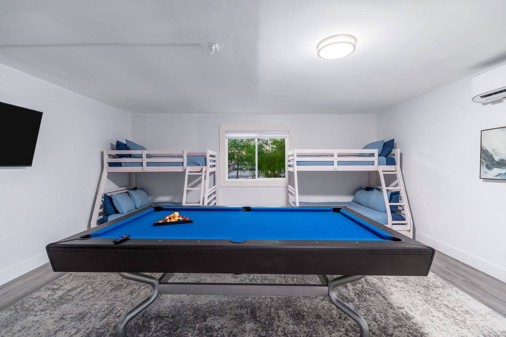 Your private game room pairs friendly competition with flexible sleeping space, featuring a full-size billiard table and cozy bunk beds wrapped in soft blue linens.