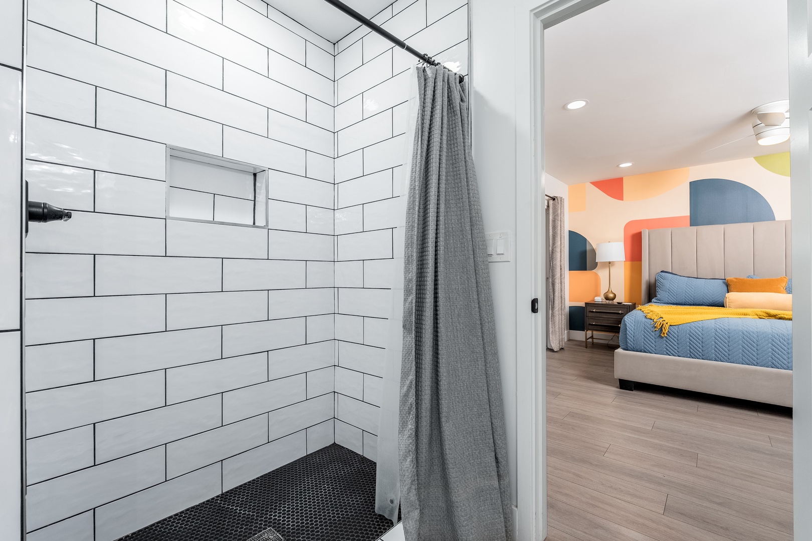 Step into your private en-suite bathroom with a sleek walk-in shower and modern tile, just steps from your vibrant bedroom retreat with playful pops of color.