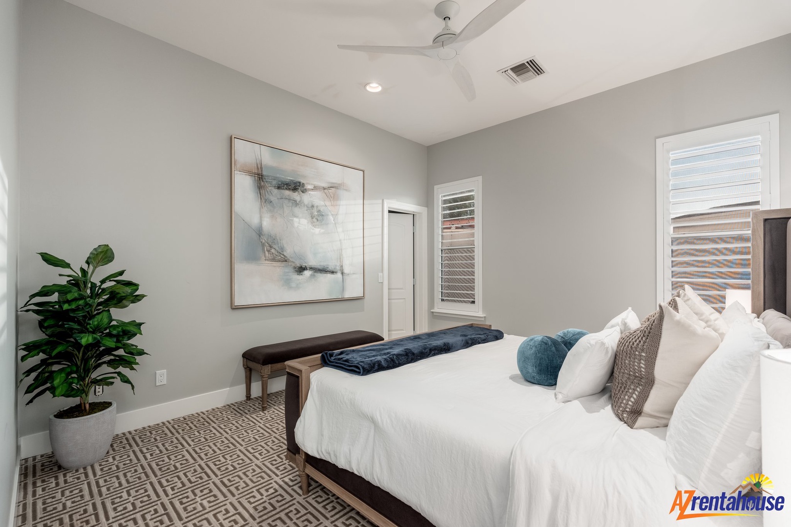 Sink into crisp white linens in your serene bedroom, where gentle ceiling fan breezes and contemporary art create the perfect retreat.