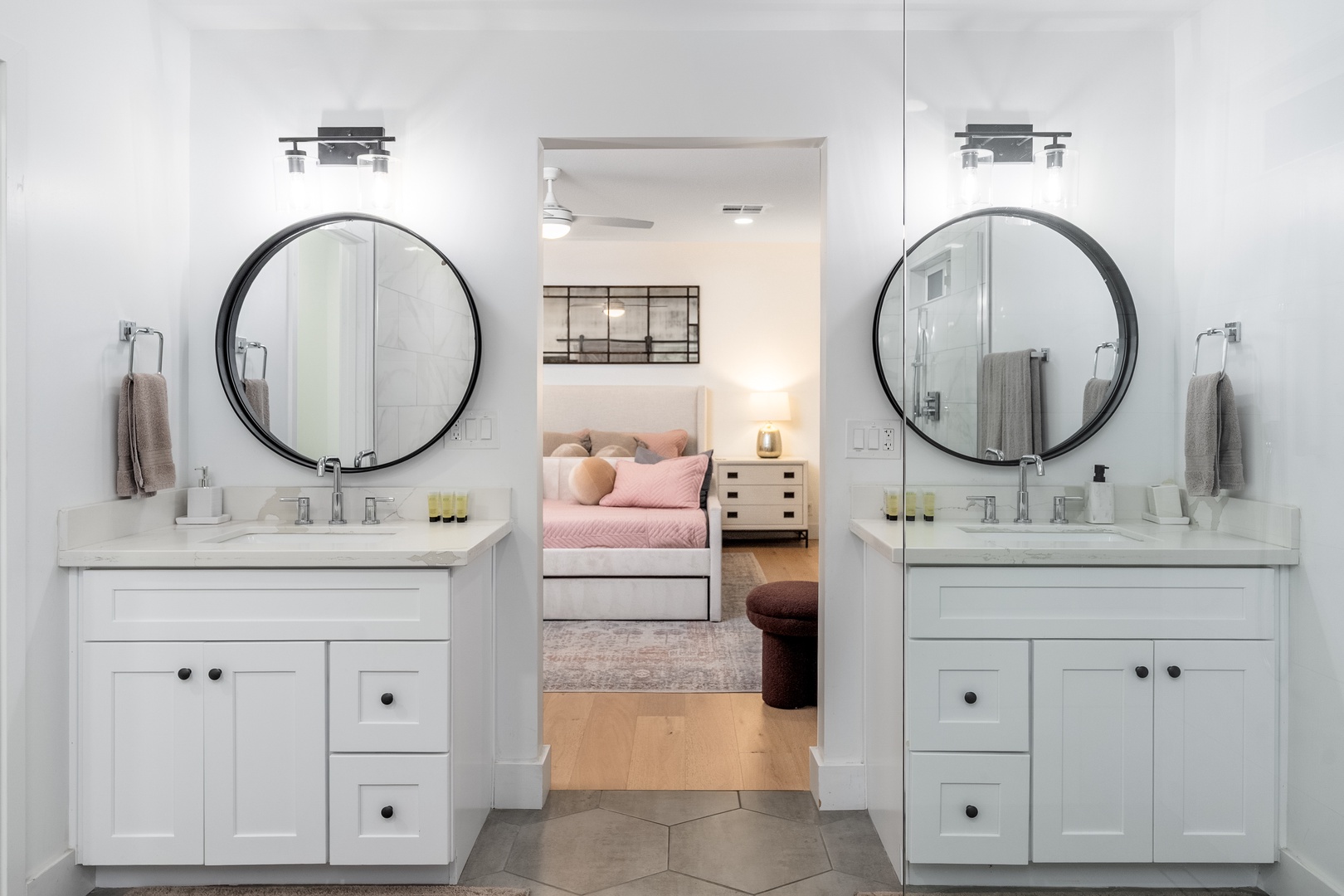 Your private bathroom features matching dual vanities with round mirrors and opens directly to your serene bedroom, blending style with everyday comfort.