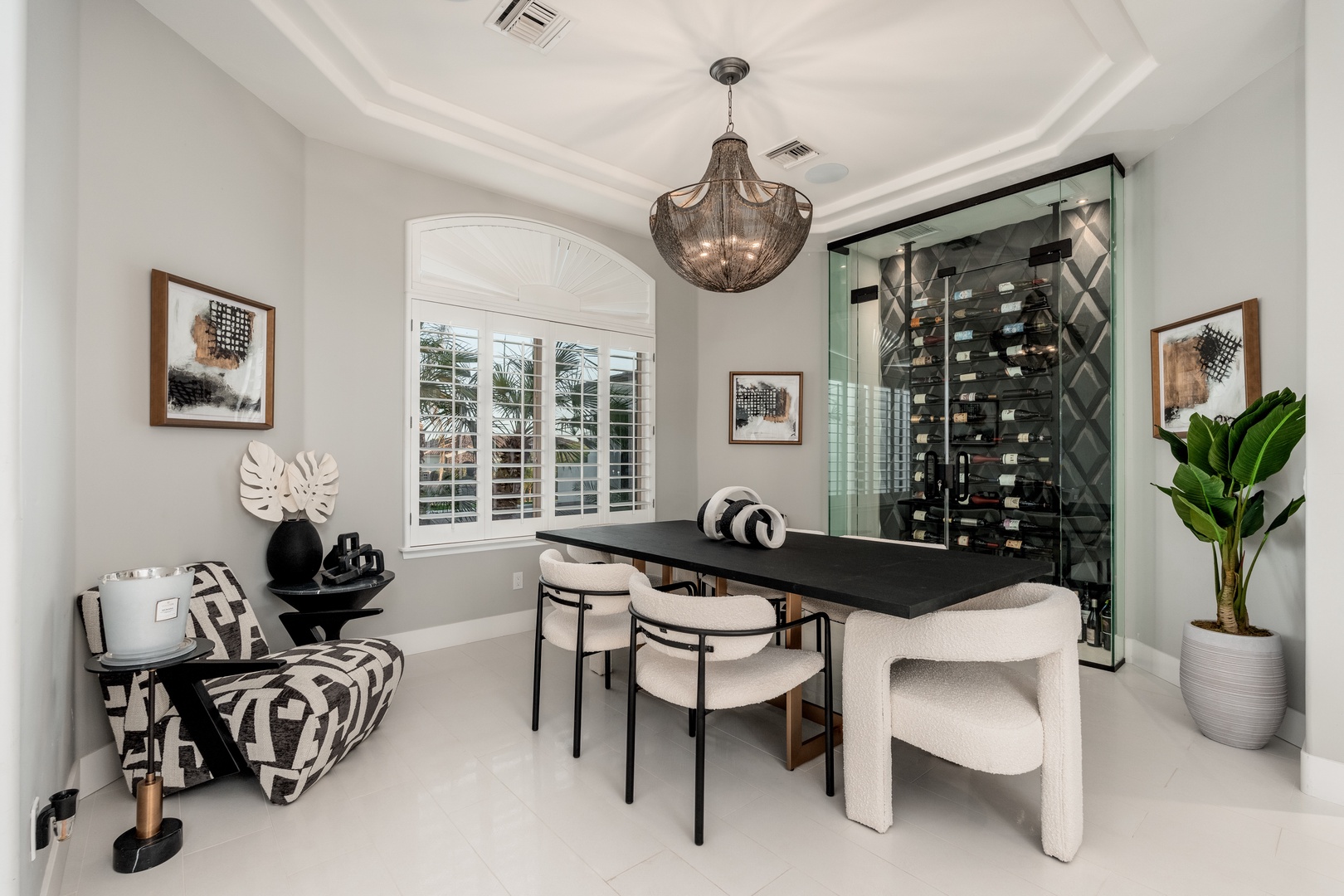 Your elegant dining space features a statement chandelier, modern seating, and a stylish glass-enclosed wine display—perfect for memorable meals and gatherings.