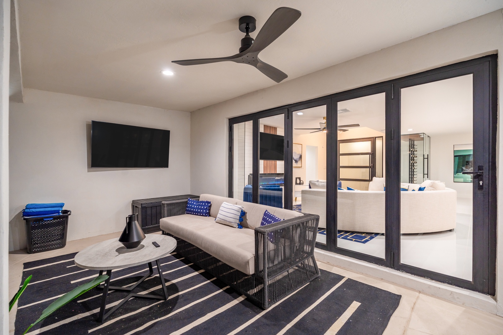 Step into your private covered patio with stylish seating, a ceiling fan overhead, and seamless glass doors inviting you into bright, open living spaces.