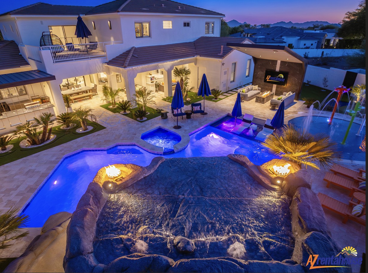 A stunning villa featuring a magnificent multi-level pool complex with hot tub and water features, all beautifully illuminated at dusk.