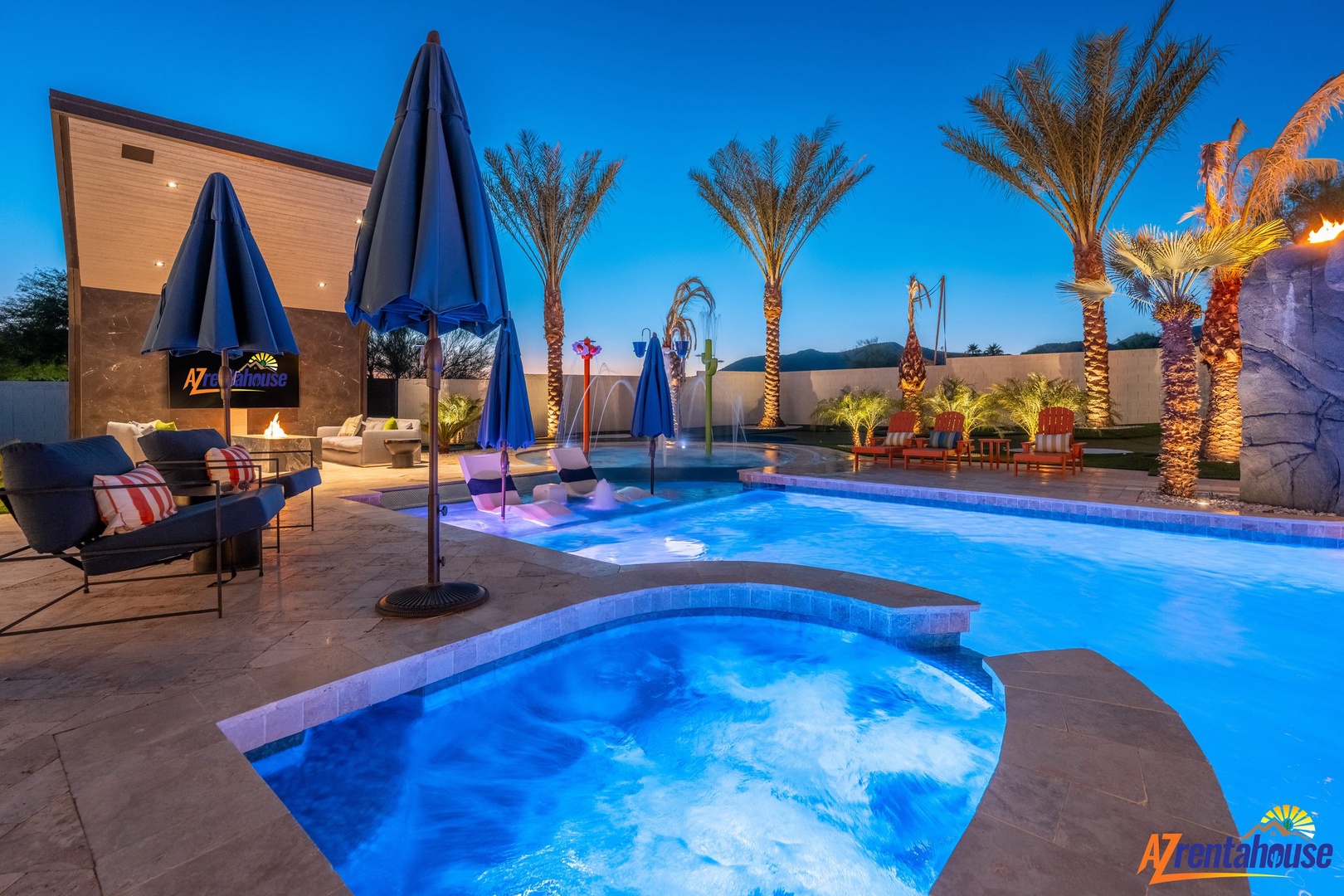 Stunning evening pool area with illuminated hot tub, palm trees, and modern outdoor living space under clear desert skies.