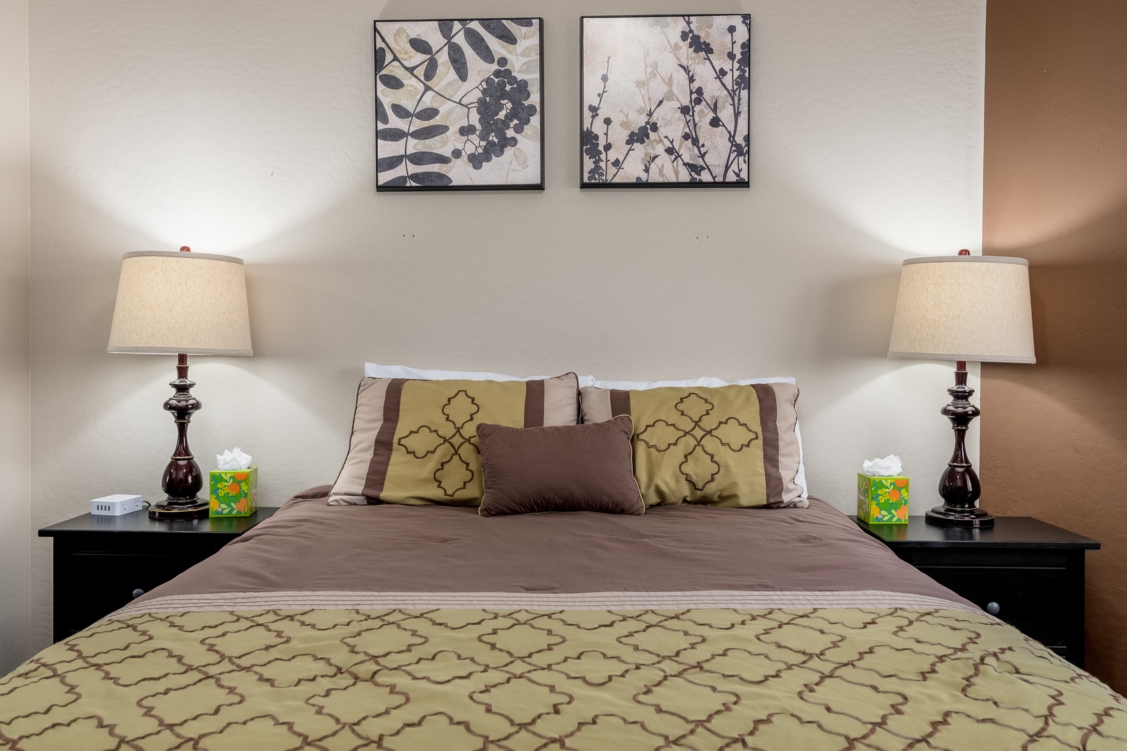 Sink into luxurious comfort on your plush bed, flanked by matching nightstands and soft lighting. Botanical art and thoughtful touches create your peaceful retreat.