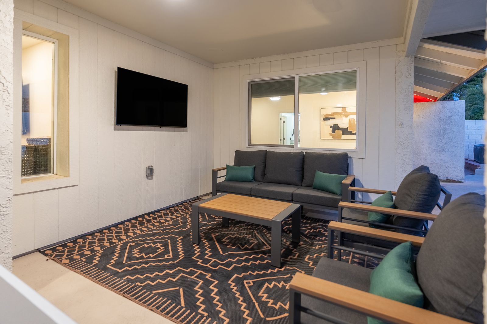Your own covered outdoor lounge awaits, complete with plush seating, a flat-screen TV, and a stylish patterned rug—perfect for unwinding after exploring.