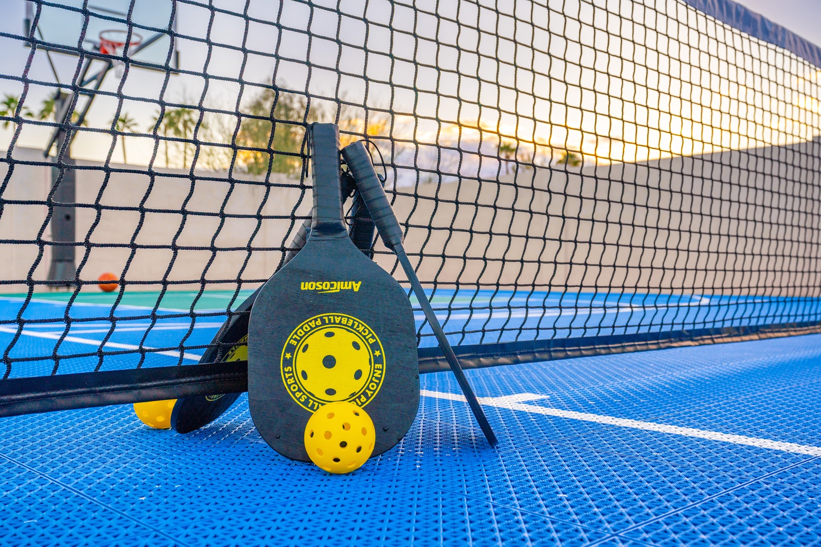 A private pickleball court awaits your friendly matches, complete with paddles and balls ready for action on the pristine blue surface.