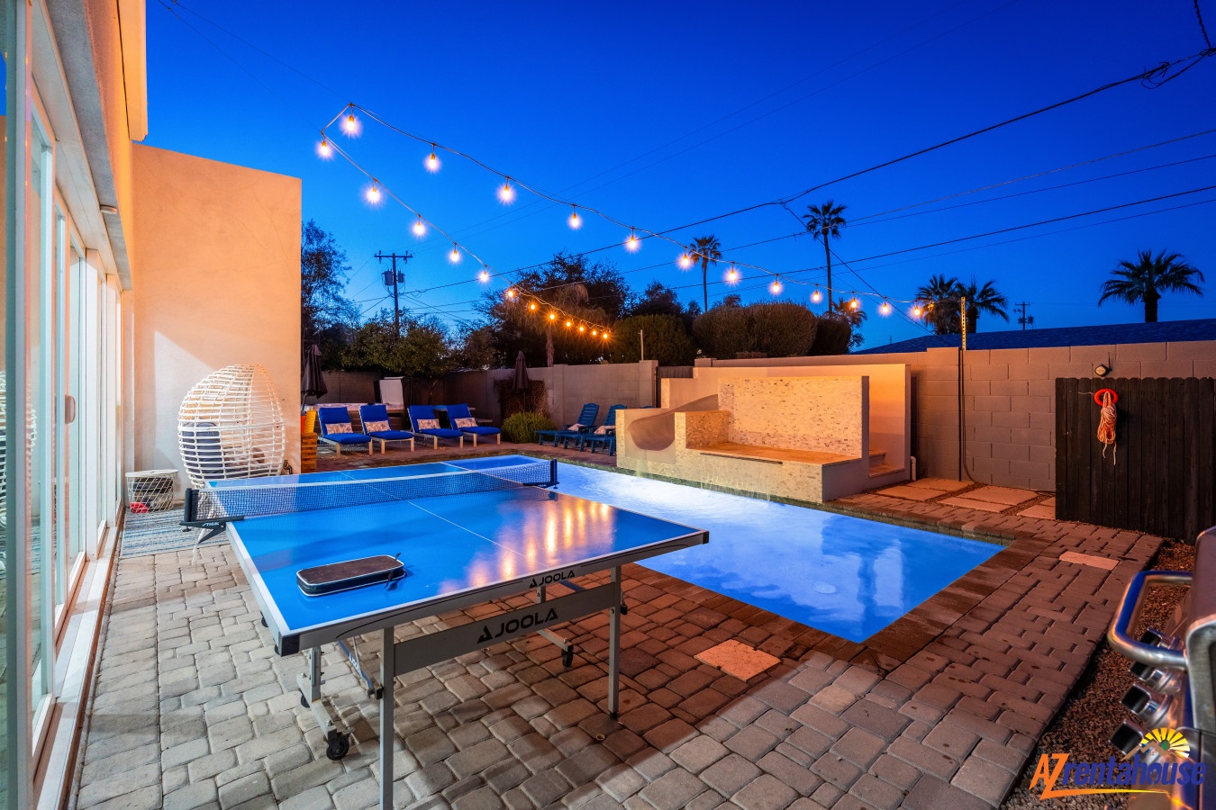 Evening magic awaits in your private backyard oasis, where string lights twinkle above the pool and ping pong promises friendly competition.