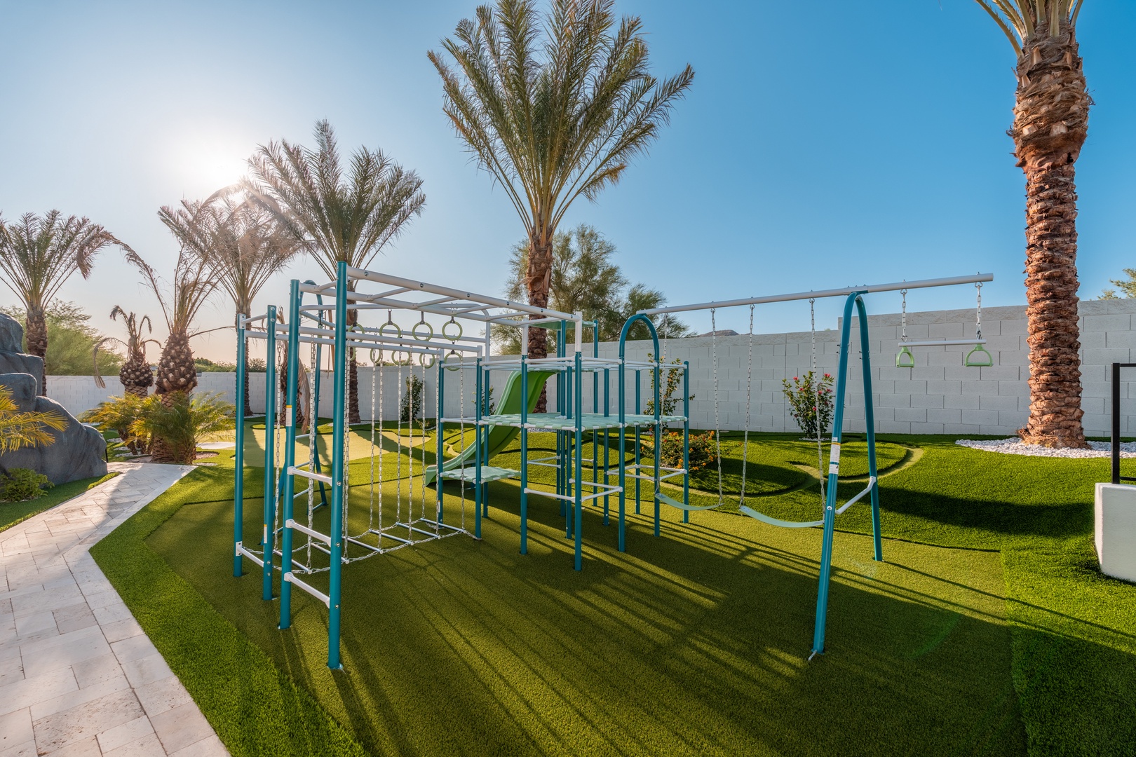 Enjoy vibrant days at the playground surrounded by lush grass and swaying palm trees, perfect for family fun under the sun.