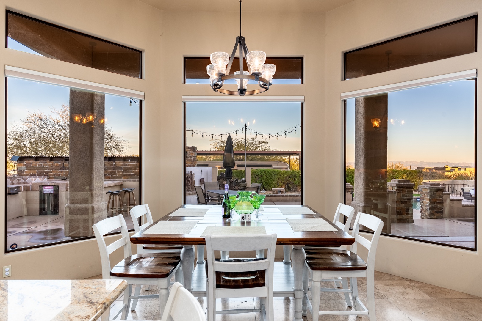 Gather around this charming dining table where your group can share meals while enjoying views of the covered patio and outdoor entertaining space through expansive windows.