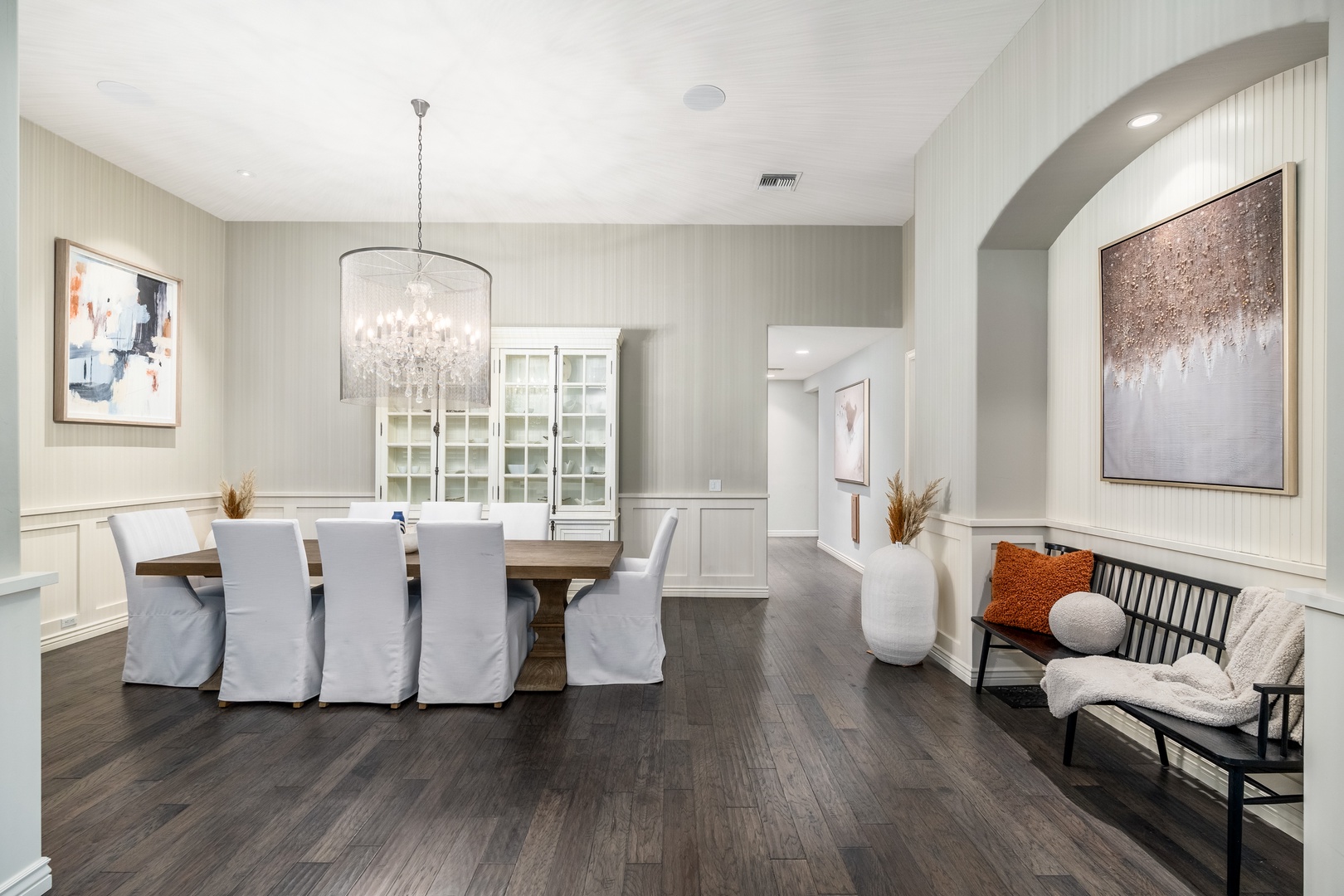 Gather around the rustic wooden table under a sparkling chandelier for memorable meals. Elegant seating, warm hardwood floors, and touches of art create your perfect dining retreat.