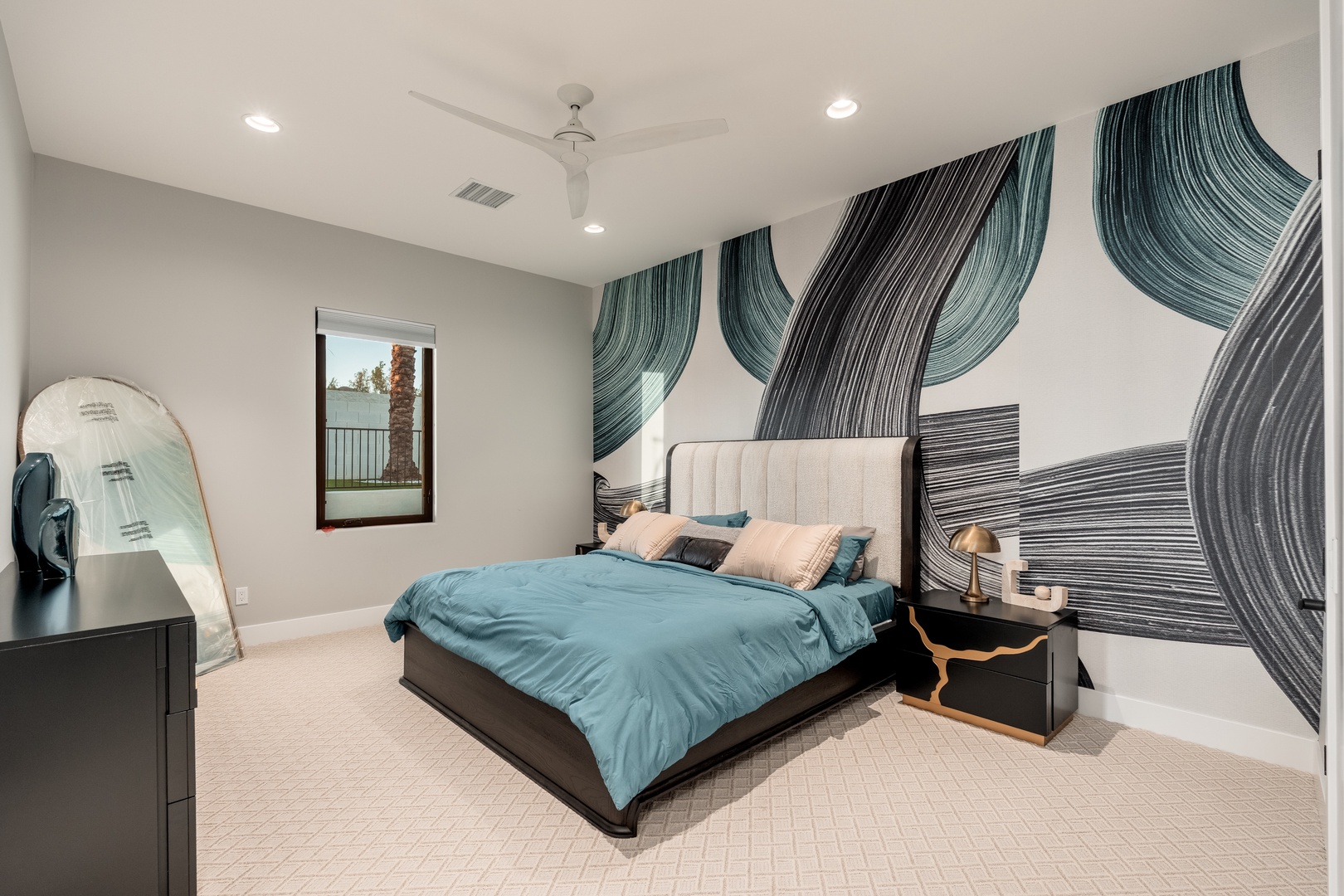 Sink into plush bedding beneath a striking wave mural, where coastal-inspired art meets modern comfort. Your peaceful retreat awaits with breathtaking views just beyond the window.