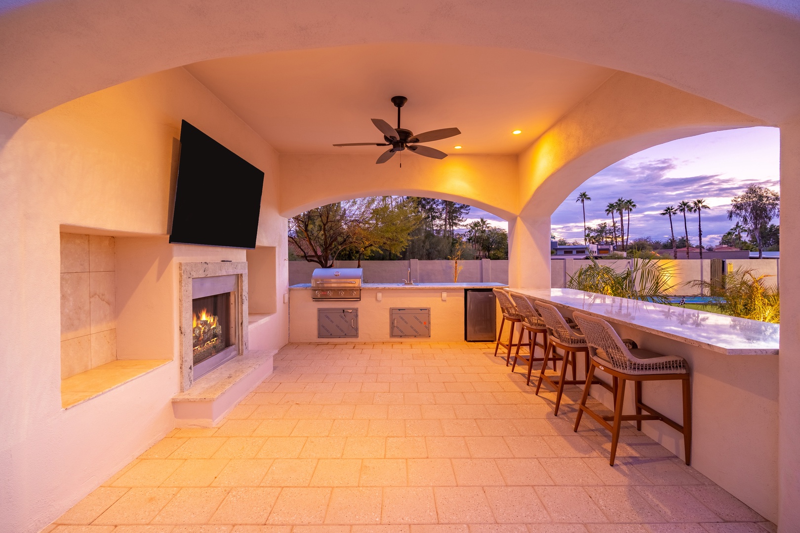 Unwind in your covered outdoor oasis with a chef's BBQ kitchen, cozy fireplace, and stunning twilight views of swaying palms—perfect for memorable evenings with friends and family.