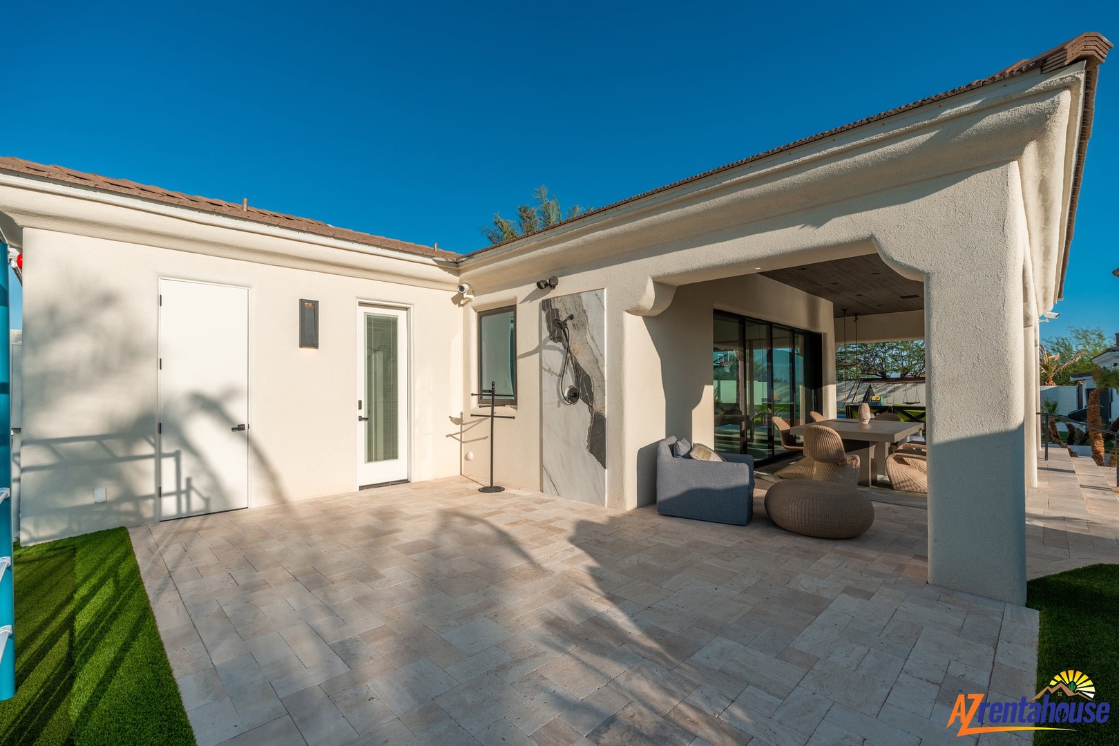 Modern vacation rental with covered patio featuring comfortable seating beneath clear desert skies.