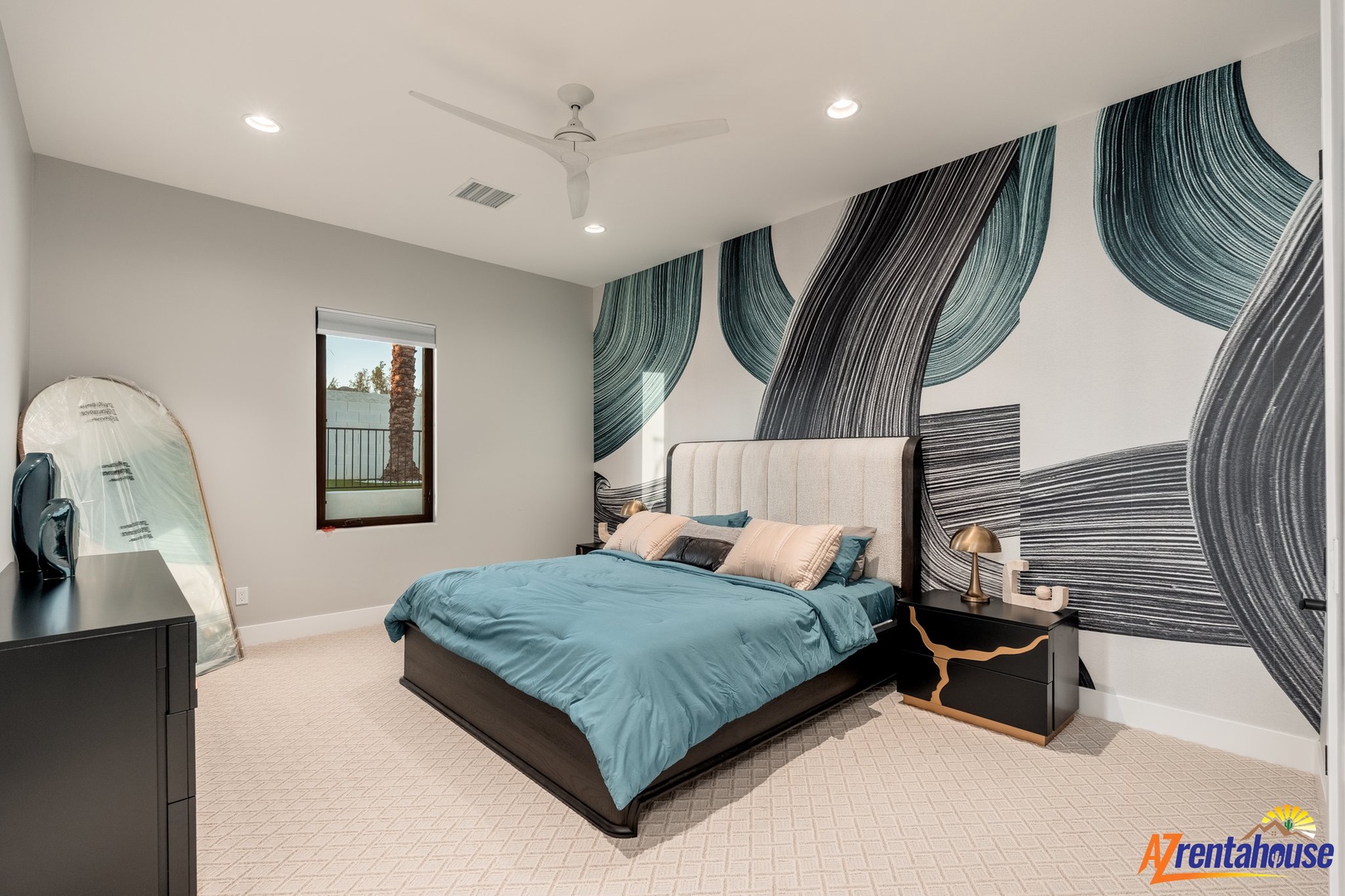 Your striking bedroom features a dramatic wave-inspired accent wall in teal and charcoal, creating an artistic backdrop for restful nights.
