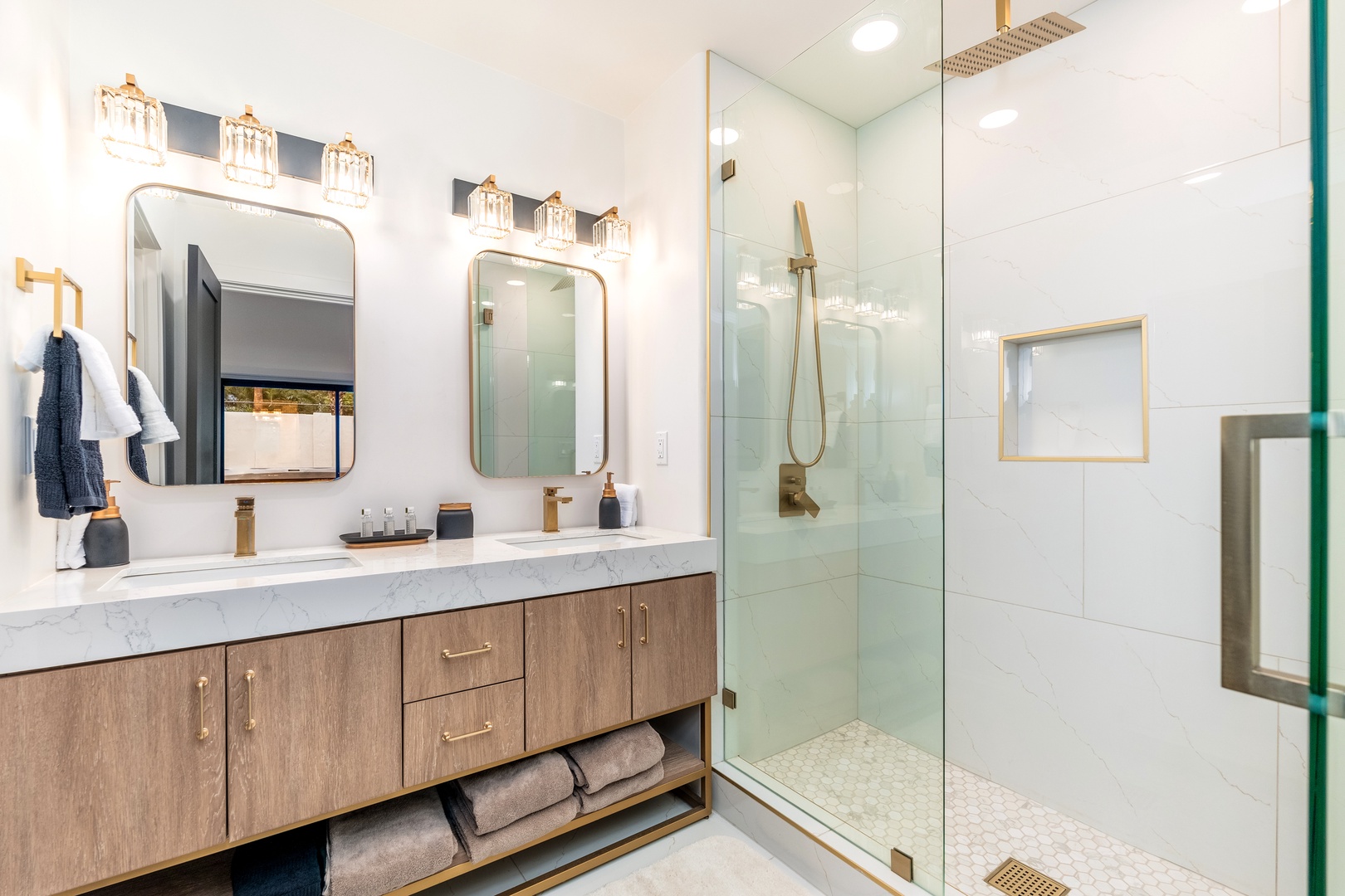 Your private retreat awaits with a spacious walk-in shower, dual vanities topped with marble, and elegant gold fixtures that gleam in the warm lighting.