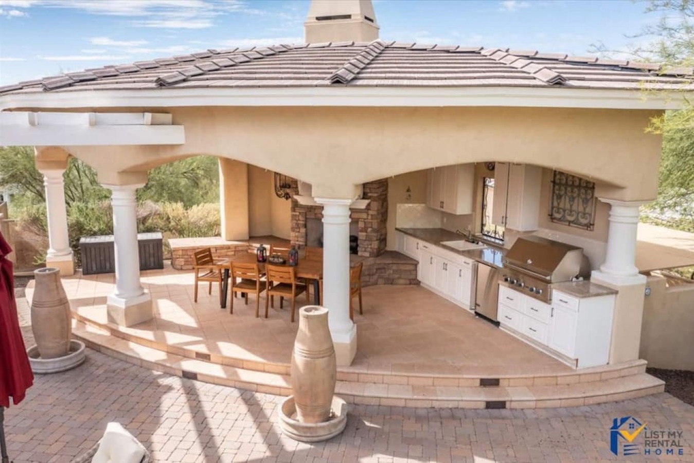 Your private outdoor kitchen awaits with premium appliances and dining space under elegant columns—perfect for memorable alfresco entertaining.