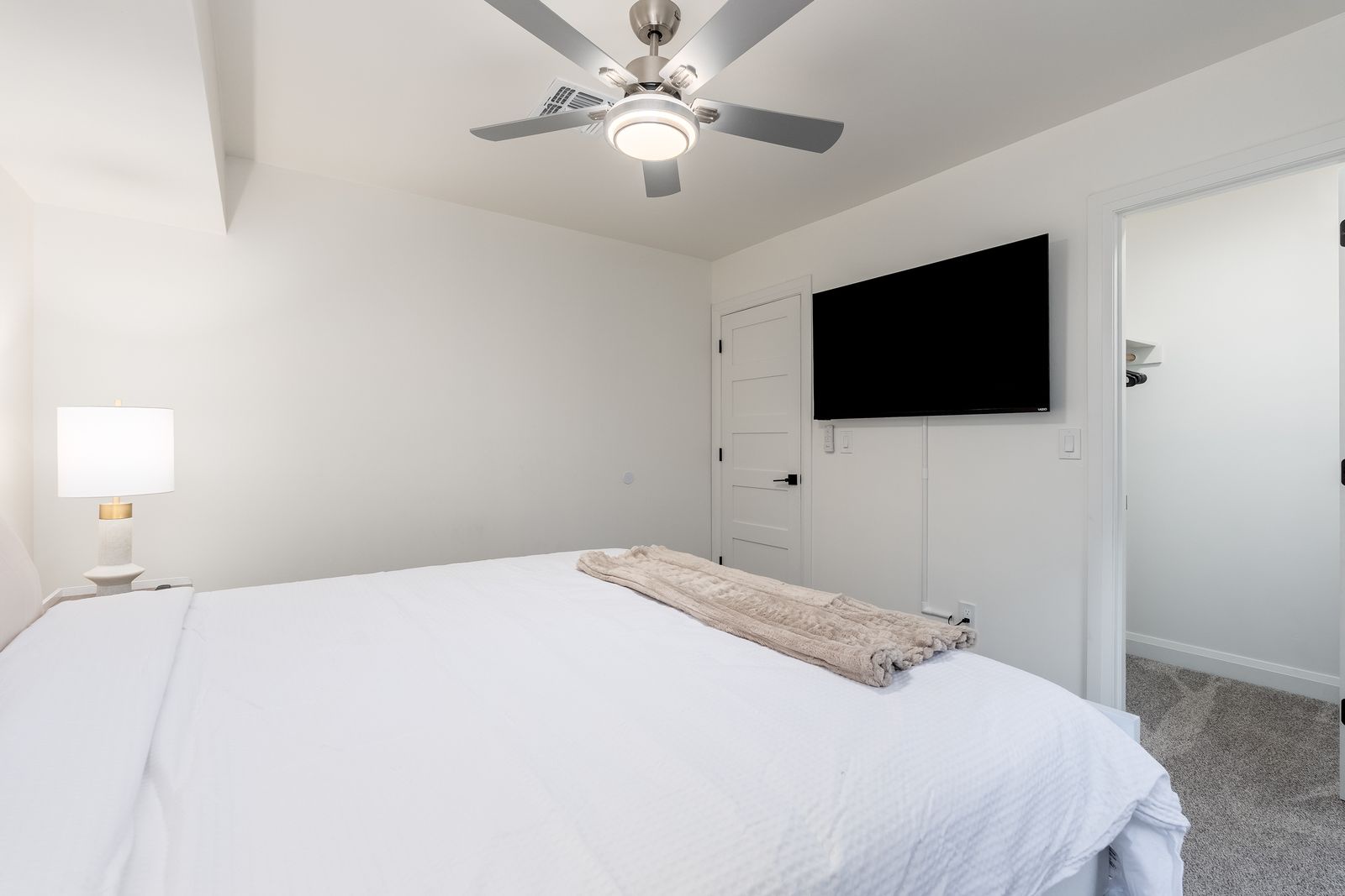 Sink into crisp white linens in your serene bedroom, complete with ceiling fan, entertainment, and soft bedside lighting for ultimate relaxation.