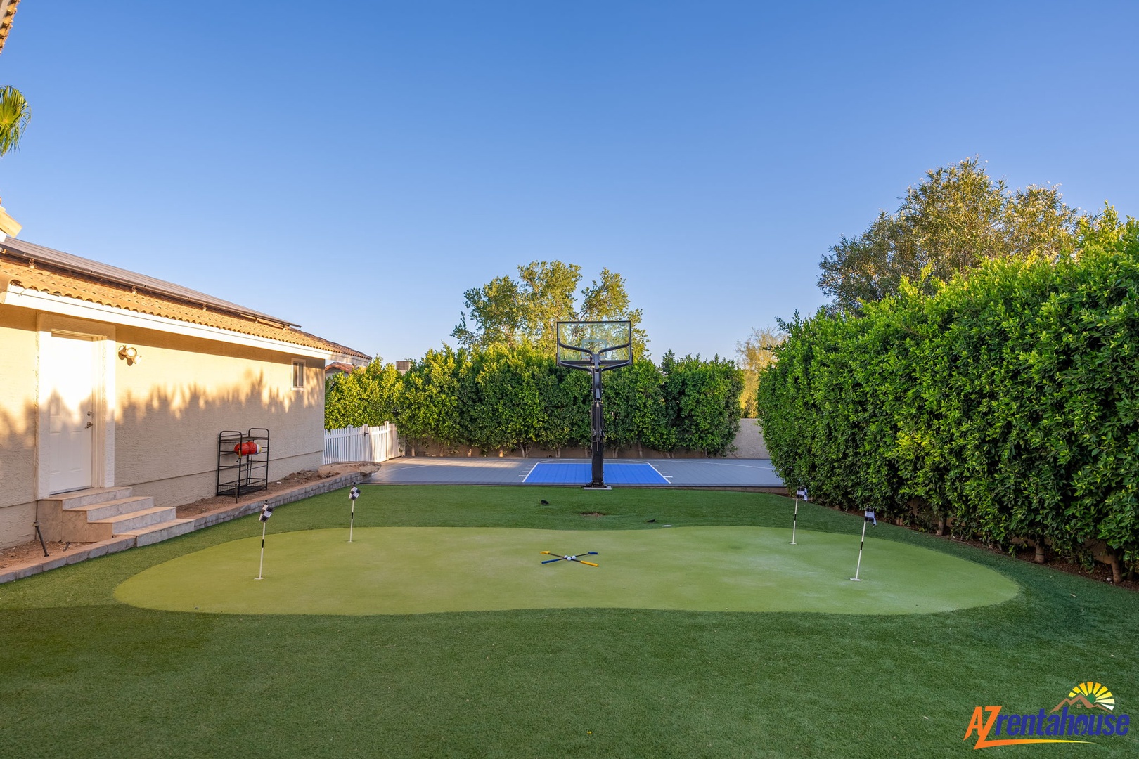 Private backyard features a putting green and basketball court, ideal for year-round outdoor recreation and family fun.