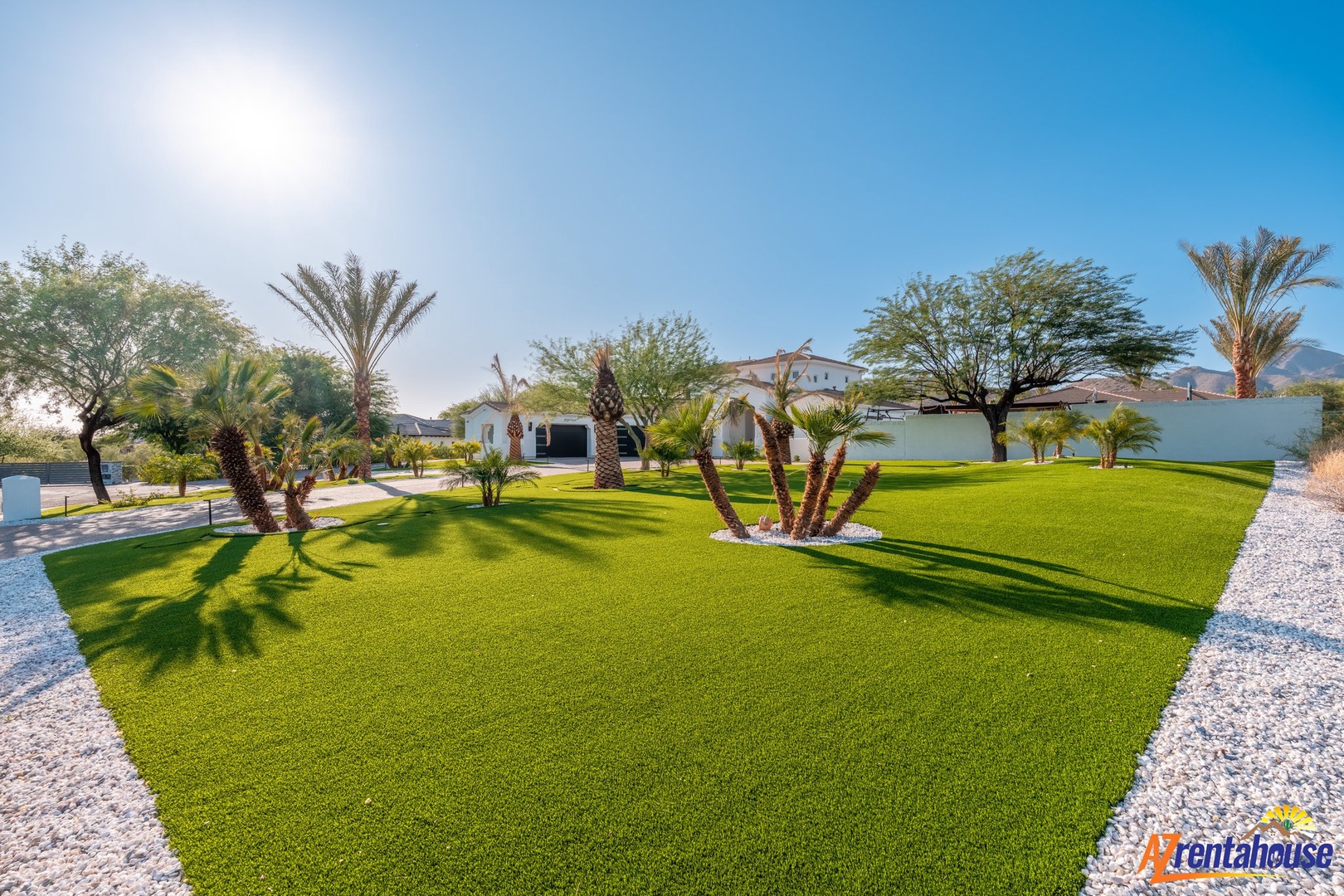 Beautiful desert oasis property with lush green lawns and palm trees under sunny skies.