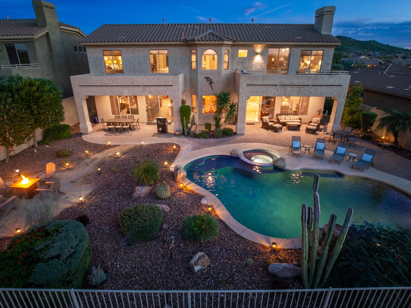 A luxurious desert oasis awaits with a stunning pool, integrated hot tub, and expansive patio—all framed by dramatic southwestern landscaping and mountain views.