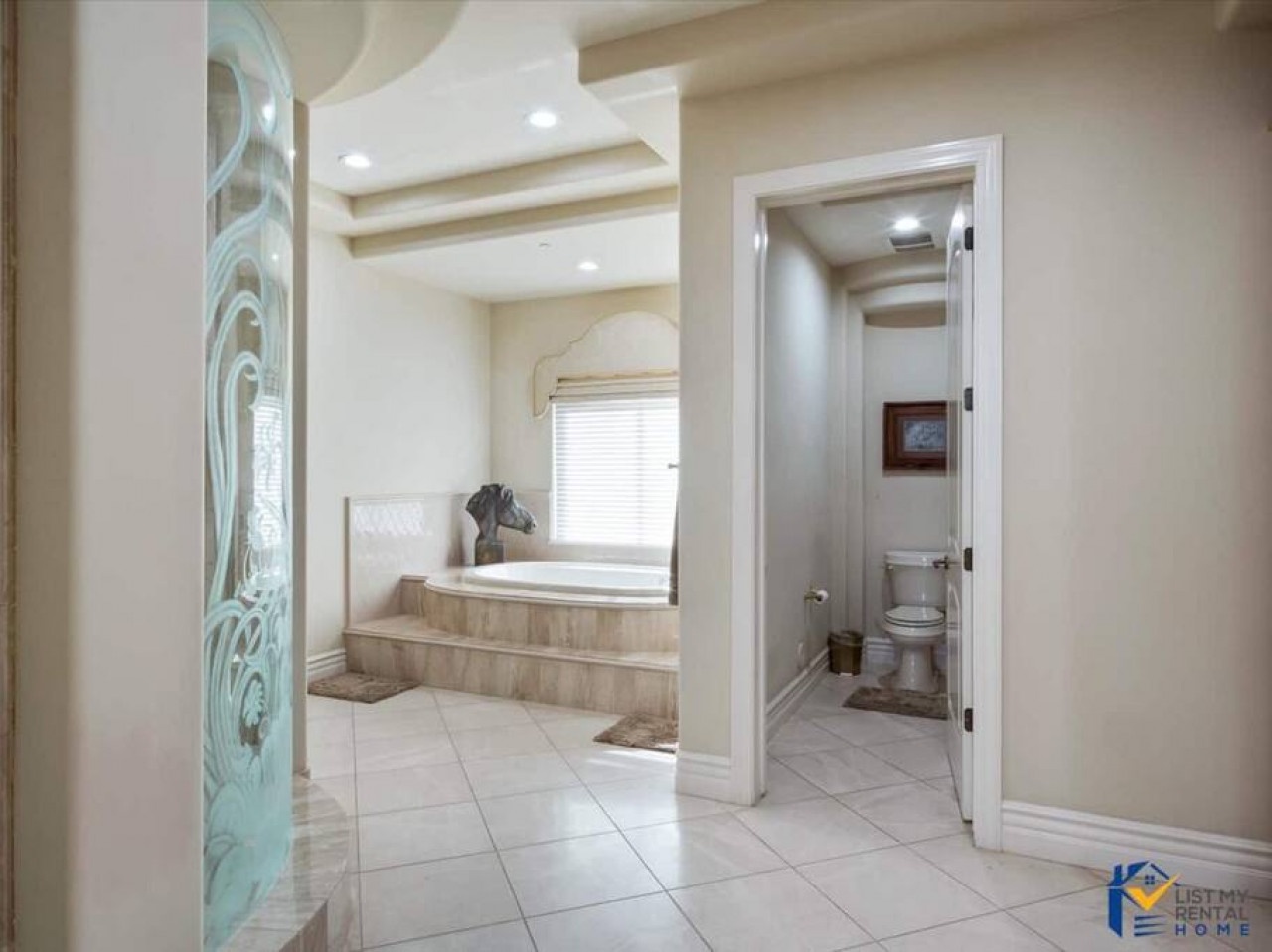 Your luxurious spa-style bathroom features a soaking tub with steps and elegant neutral tones throughout.