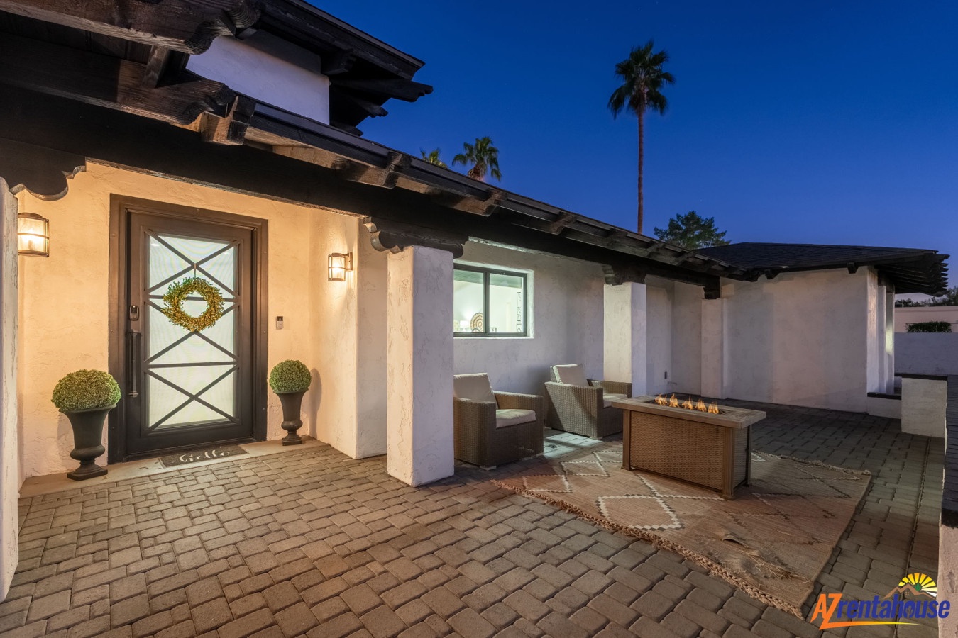 Cozy evening patio awaits with crackling fire pit, comfortable seating, and charming entrance to your desert retreat.