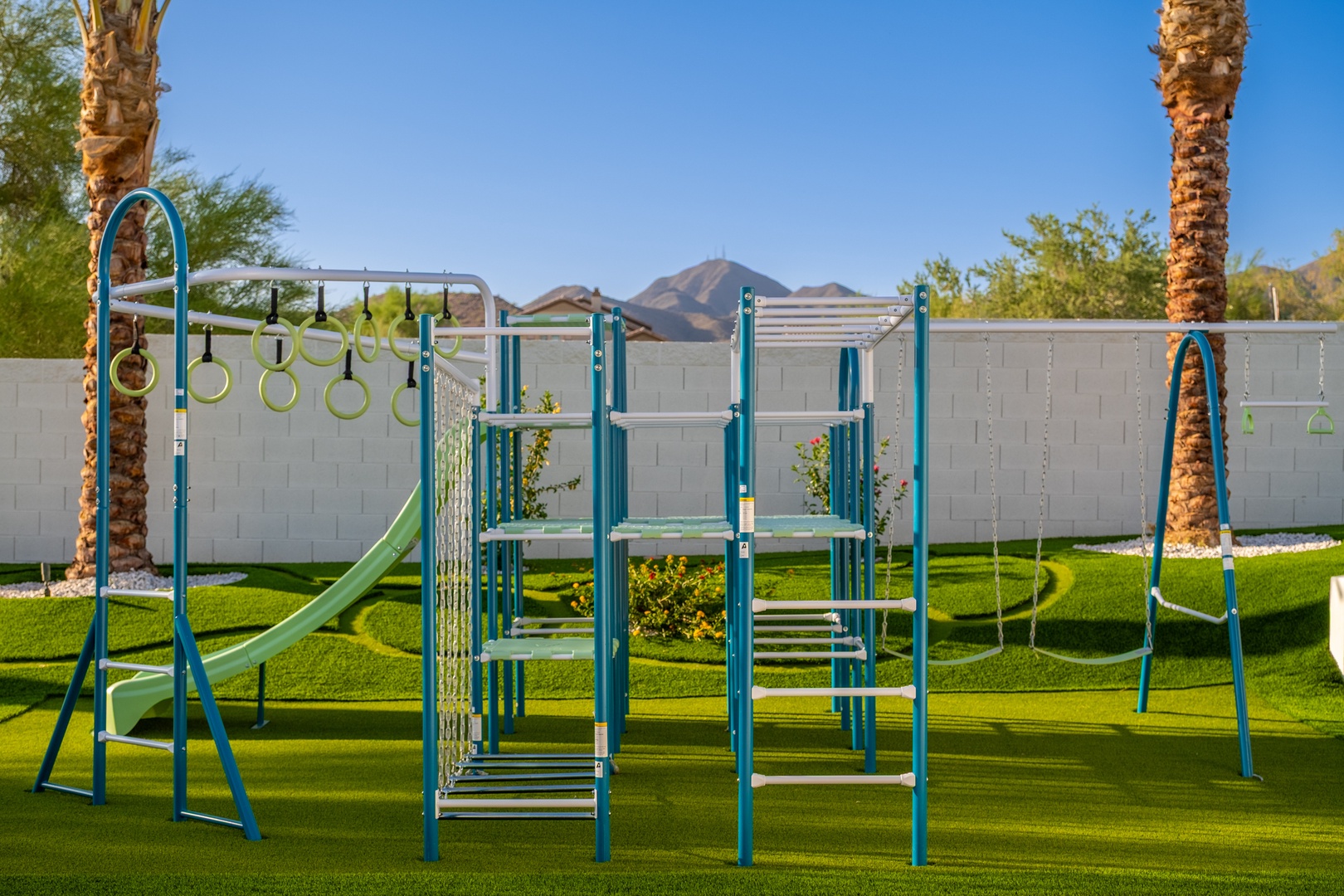 A well-equipped playground awaits in a spacious, manicured yard with mountain views, offering safe outdoor fun for families traveling with children.