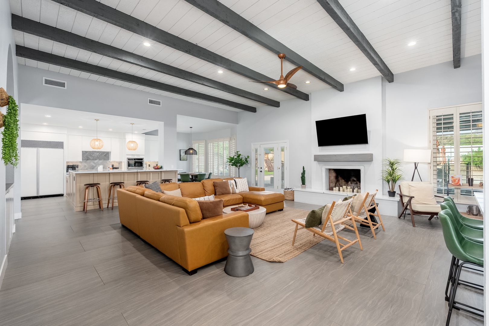 Relax in your spacious open-concept living space featuring soaring vaulted ceilings, exposed beams, and a cozy fireplace. The modern furnishings and warm tones create the perfect atmosphere for unwinding after a day of adventure.