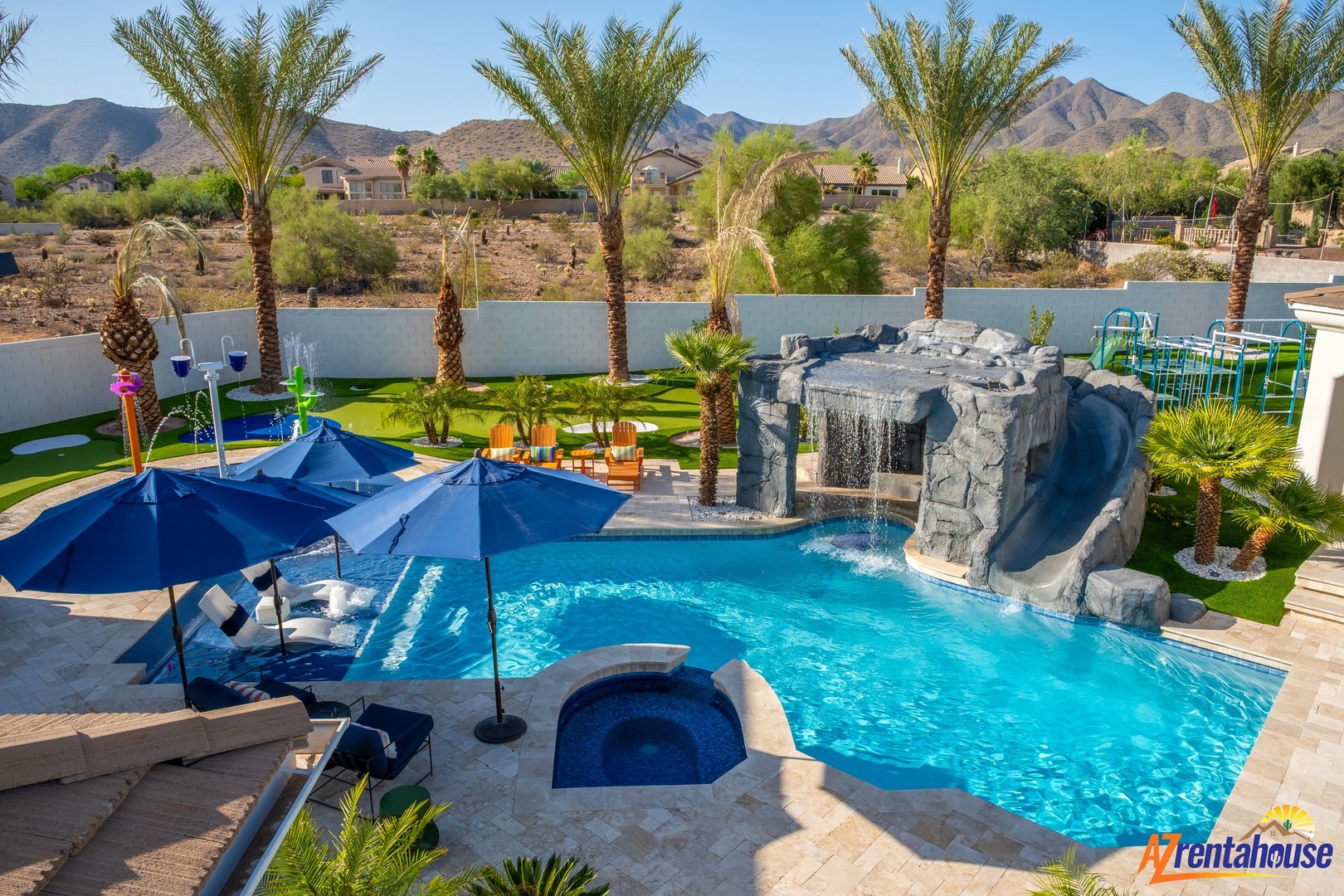 Backyard oasis with sparkling pool, waterfall grotto, and mountain views creating your perfect desert escape.