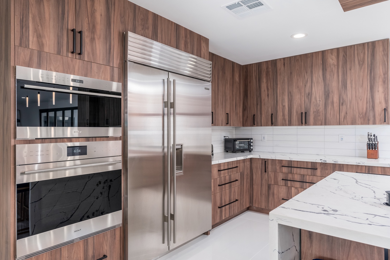 Your fully equipped kitchen features sleek stainless-steel appliances, including a double oven and spacious refrigerator, alongside stunning marble countertops—perfect for preparing memorable meals.
