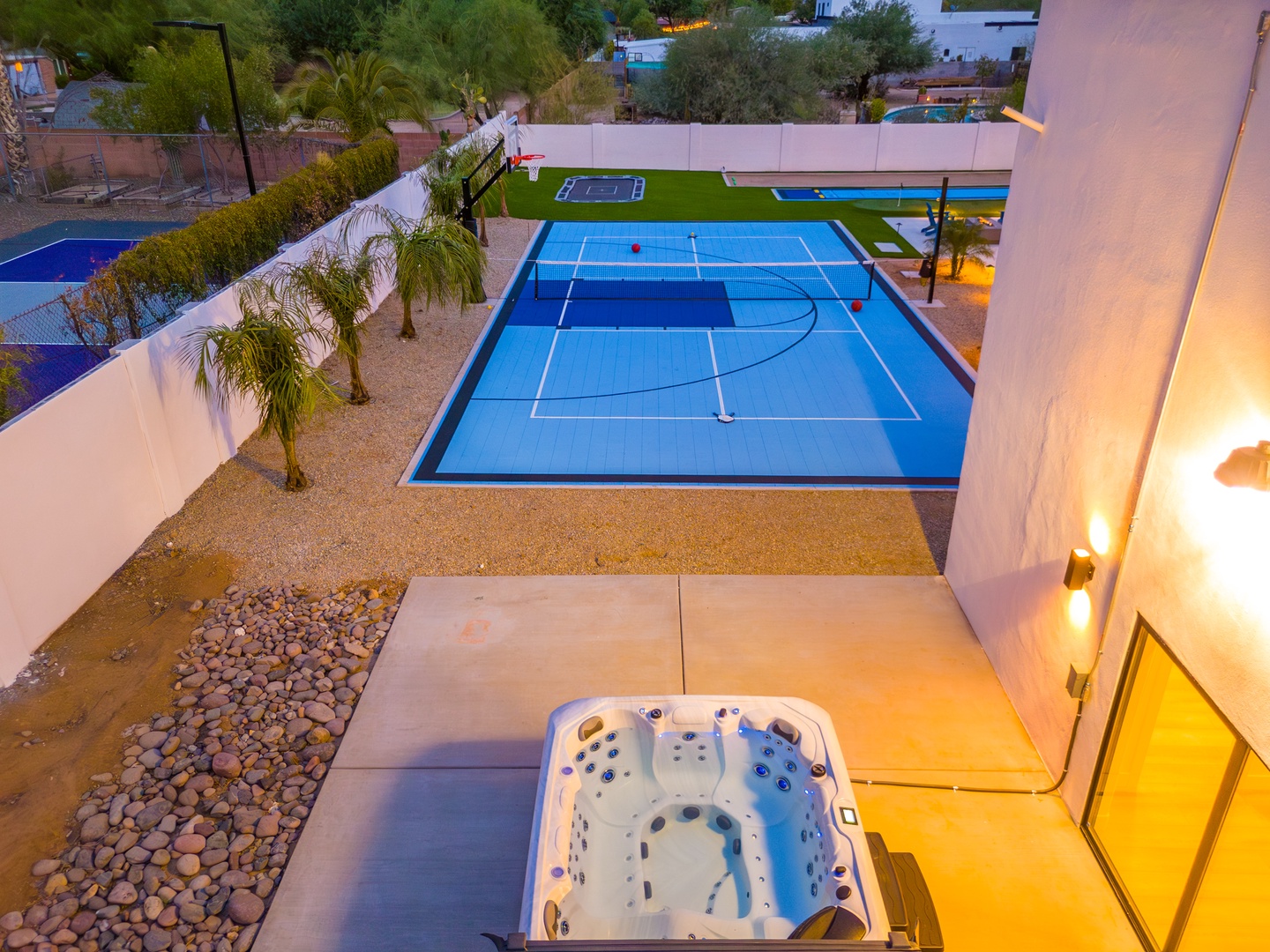 The property features a private sports court with basketball and tennis markings, tropical landscaping, heated pool, and hot tub—perfect for active relaxation in a beautifully designed setting.