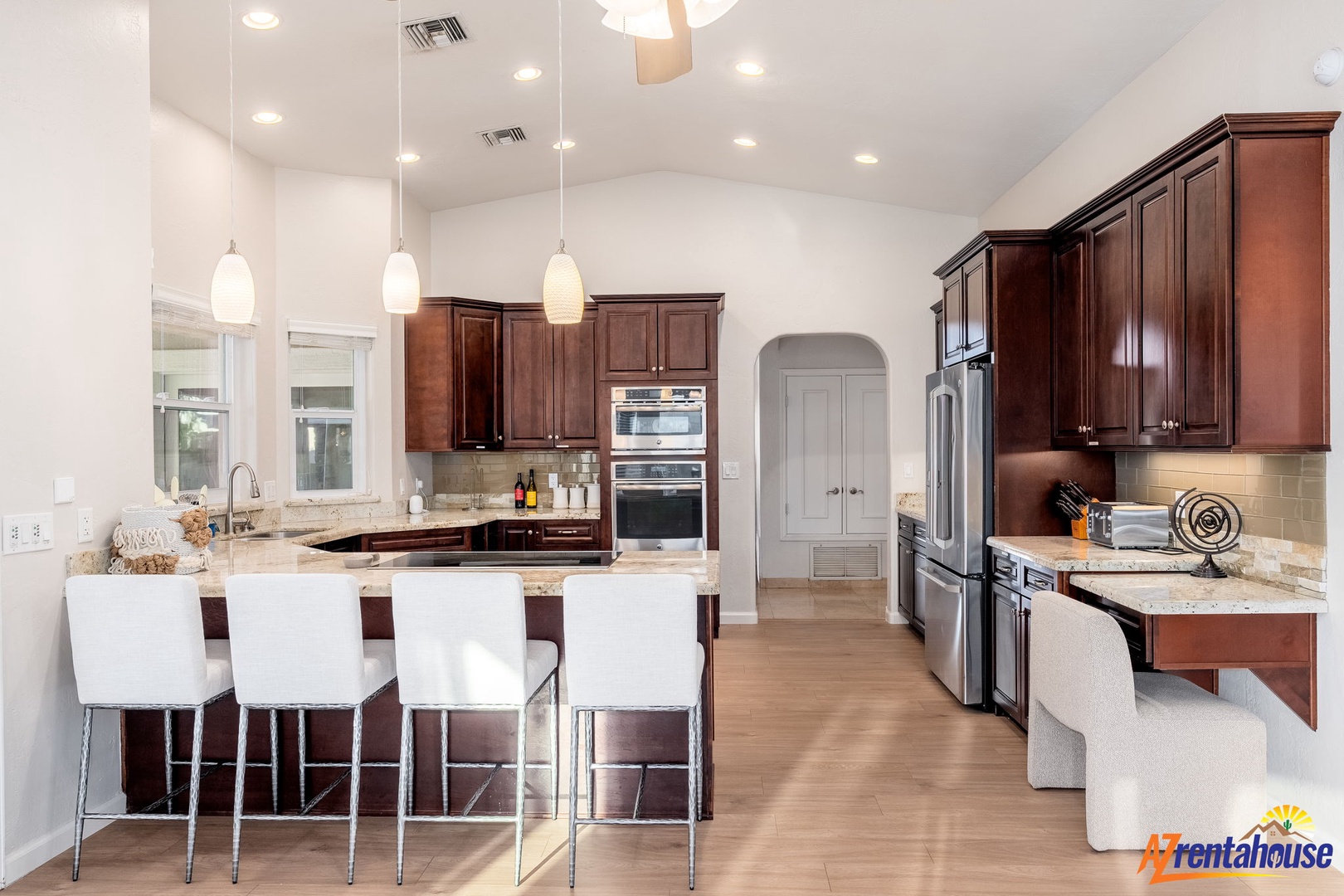 Picture yourself preparing meals in this spacious, light-filled kitchen with rich wood cabinetry, gleaming granite countertops, and modern stainless appliances—perfect for gathering and cooking together.